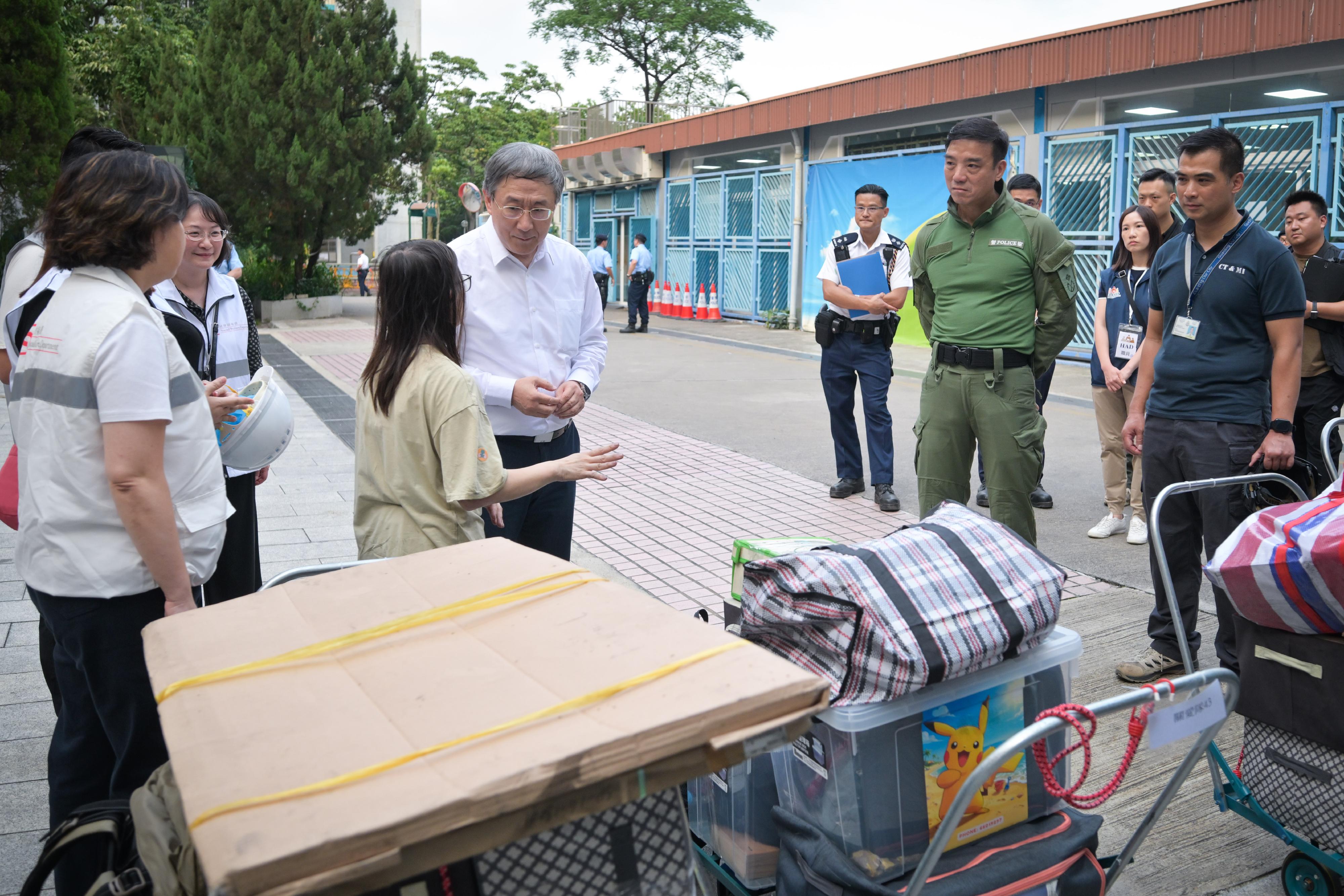 The Deputy Chief Secretary for Administration, Mr Cheuk Wing-hing, today (April 21) inspected the arrangements for Tai Po Wang Fuk Court residents returning to their units. Photo shows Mr Cheuk talking with a member of a Wang Sun House household who are waiting for transport at Tai Po Baptist Public School after returning to their unit. One of the household members said that she was pleased to be able to retrieve a number of items from their unit, and the staff were very helpful during the entire process.
