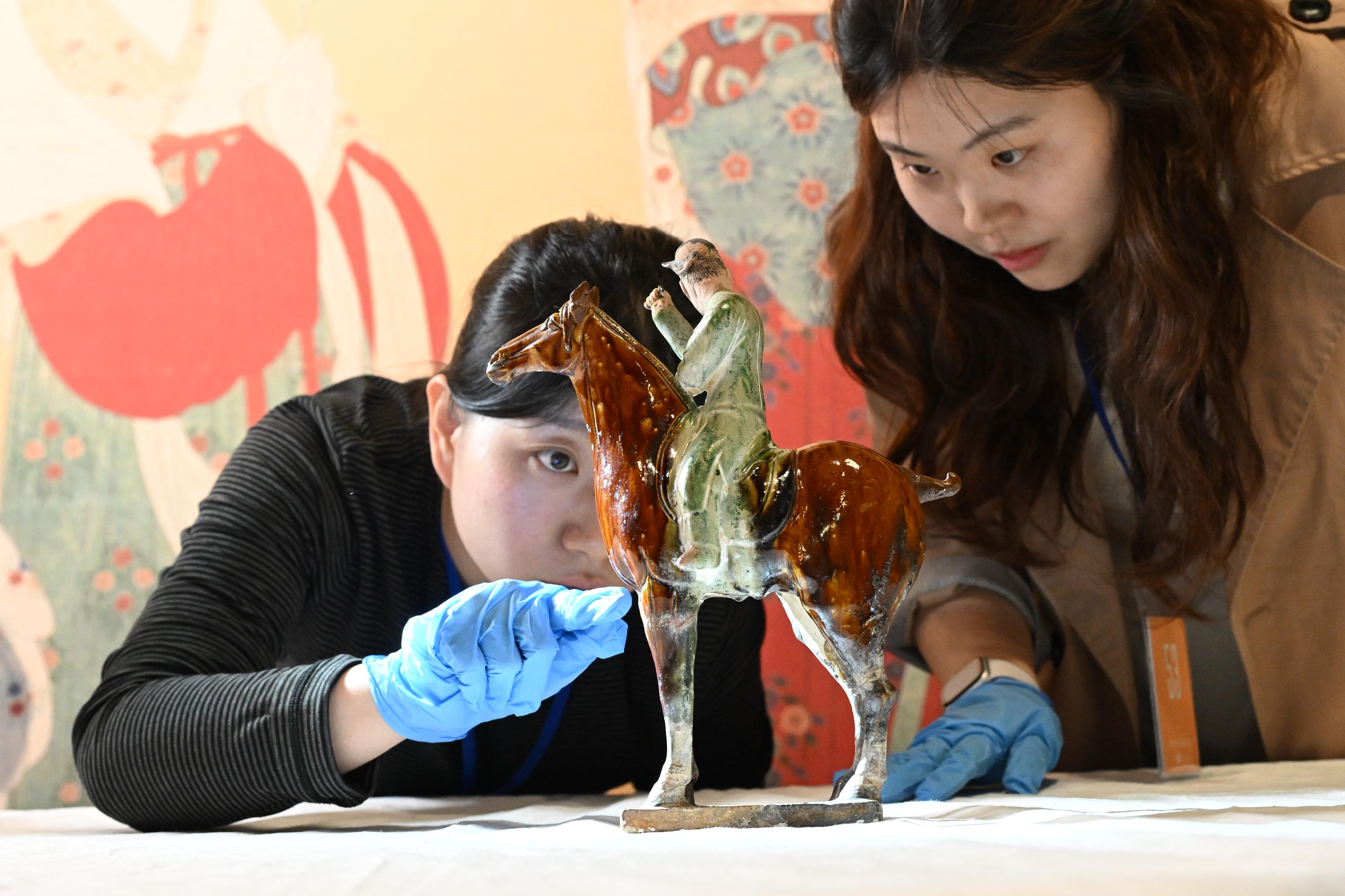 "The Hong Kong Jockey Club Series: Prosperity and Magnificence - Civilisation of the Sui and Tang Dynasties in Shaanxi Province&rdquo; exhibition will be held at the Hong Kong Museum of History from April 25 to August 24. Photo shows Chinese Mainland experts performing a condition check on a Sancai (tri-colour) glazed figurine of a hunter on horseback. In this piece, the horse is standing still, while the hunter twists his head back with a raised arm. Originally, there would have been a hunting animal behind him.
