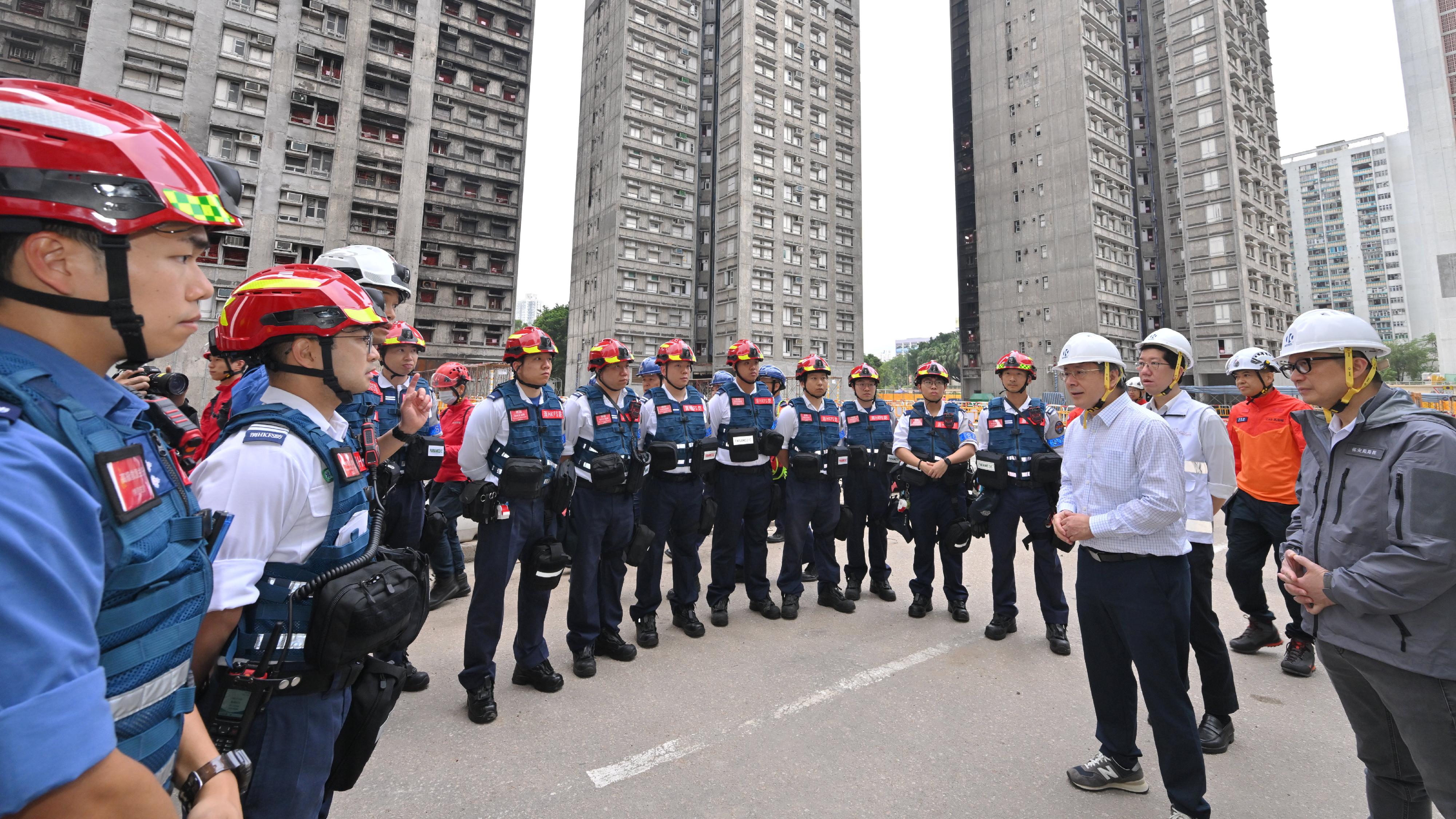 政務司副司長卓永興和保安局局長鄧炳強今日（四月二十三日）視察大埔宏福苑宏昌閣和宏仁閣居民上樓安排。圖示卓永興（右四）和鄧炳強（右一）勉勵消防處人員緊守崗位，在現場提供緊急和醫療服務。