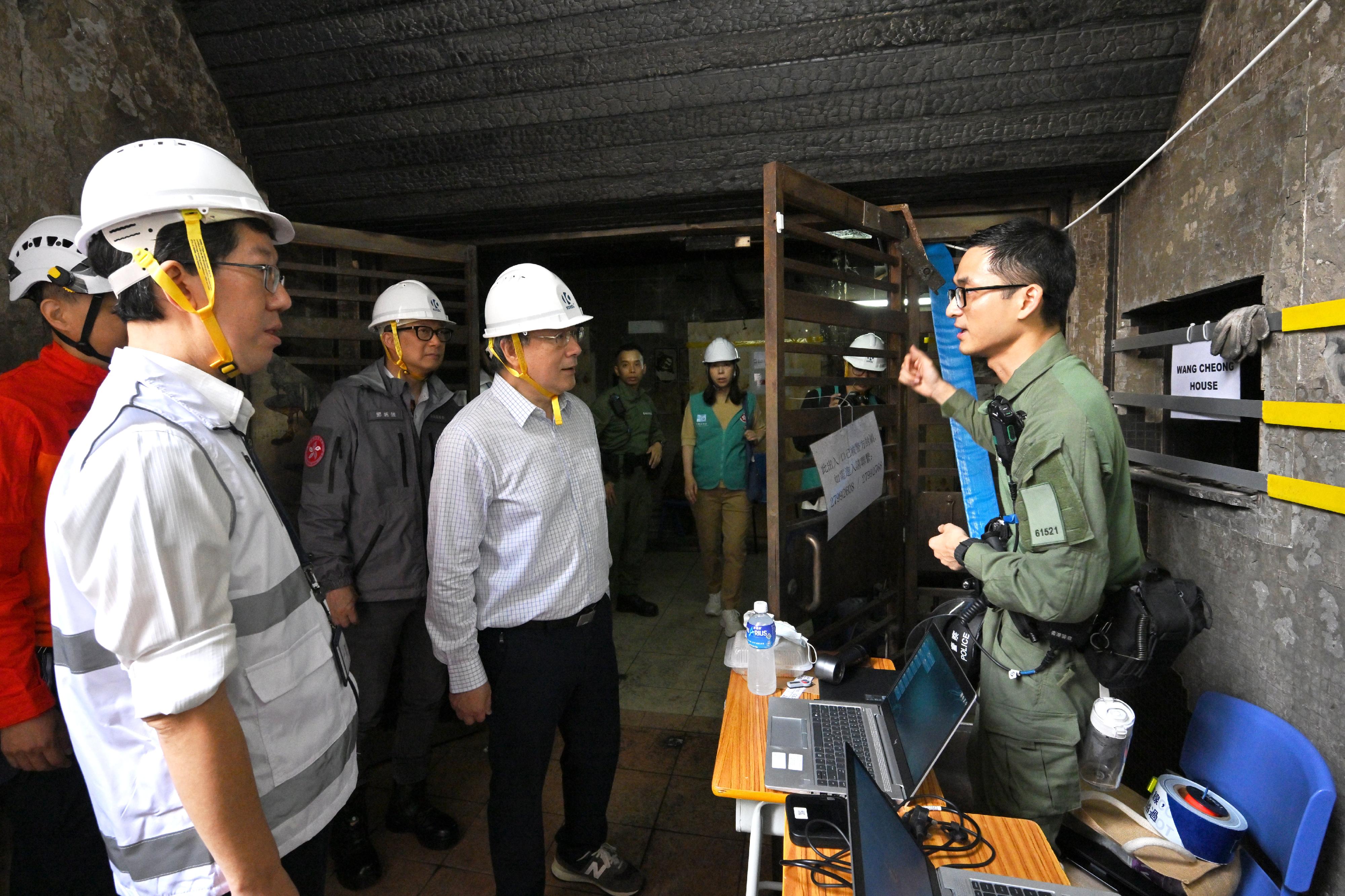 政務司副司長卓永興和保安局局長鄧炳強今日（四月二十三日）視察大埔宏福苑宏昌閣和宏仁閣居民上樓安排。圖示卓永興（左三）和鄧炳強（左二）與駐守宏昌閣地下大堂的警員交談。旁為社會福利署署長杜永恒（左一）。
