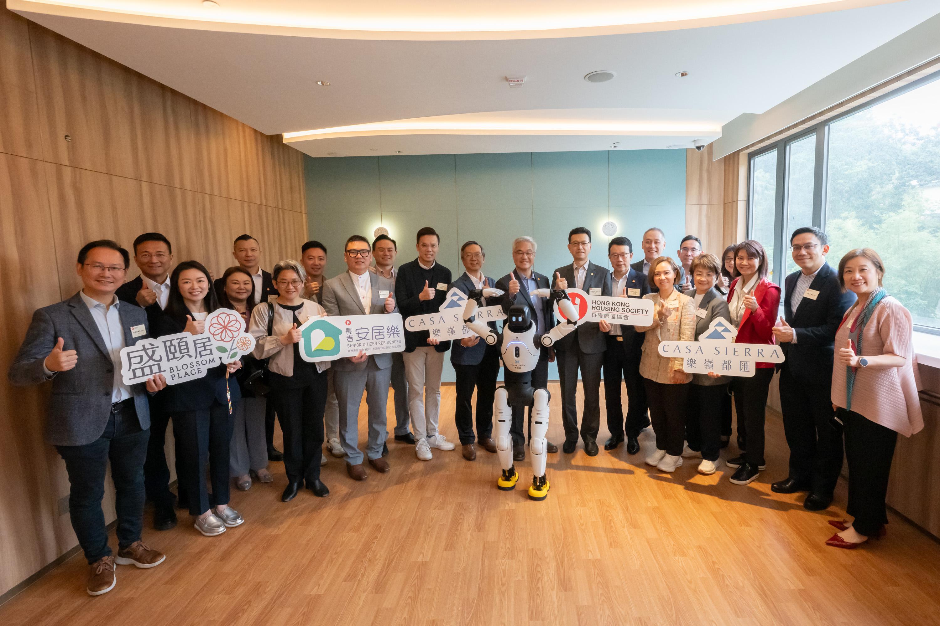 The Legislative Council Panel on Housing visited the Hong Kong Housing Society's (HKHS) Dedicated Rehousing Estate Casa Sierra in Fanling today (April 24). Photo shows the Chairman of the Panel on Housing, Mr Stanley Ng (front row, seventh right), the Deputy Chairman, Mr Leung Man-kwong (front row, 10th right), and other Members with the Government and HKHS representatives and a robotic personal trainer.
