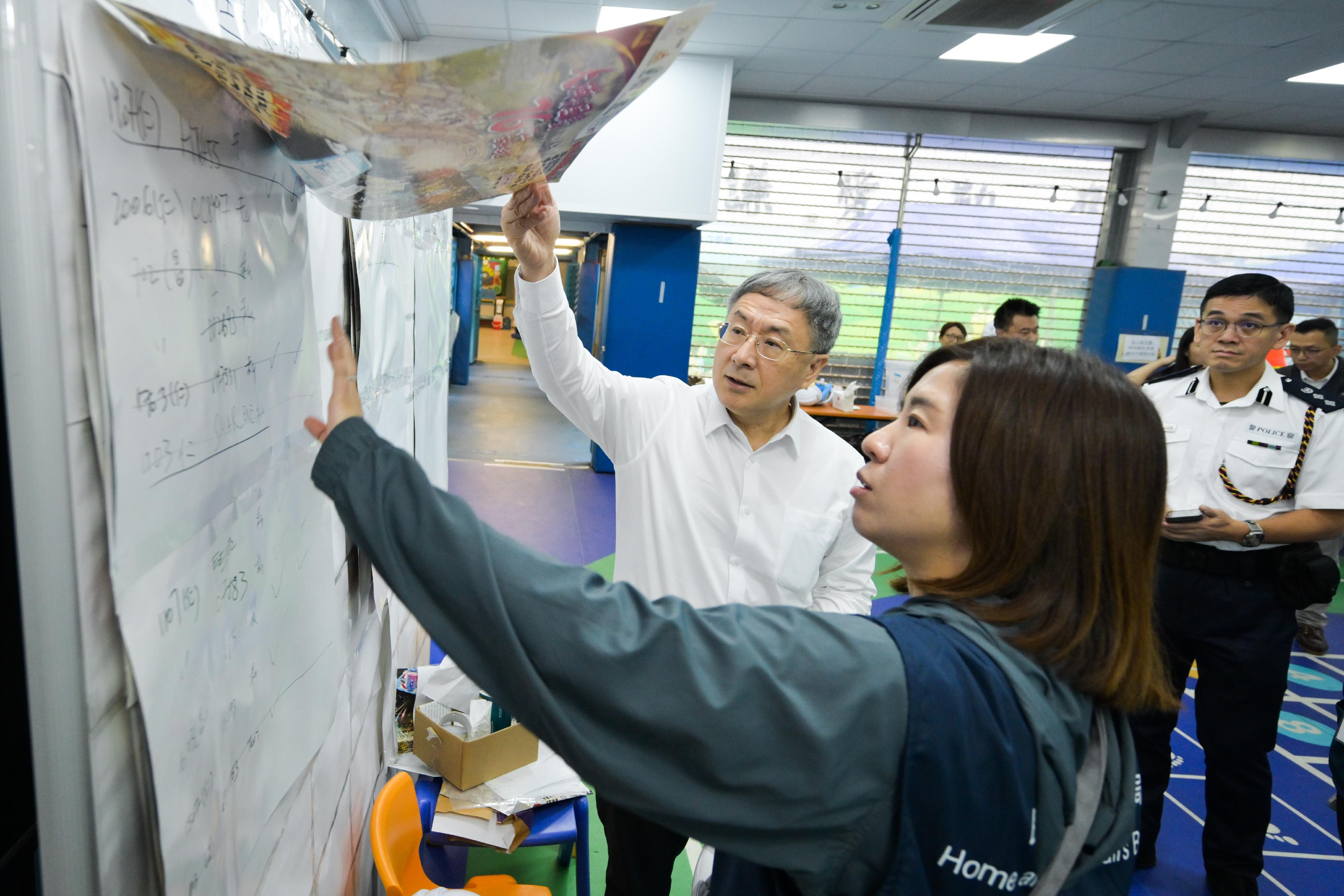 政務司副司長卓永興今日（四月二十四日）到大埔宏福苑，視察第二輪上樓安排同時開放兩幢樓宇的運作情況，以及雨天下的操作。卓永興先巡視在大埔浸信會公立學校設立的住戶等候區了解民政事務總署為等候居民提供的支援及安排預約車輛的服務；及後到物品儲存區了解同時開放兩幢樓宇後物品暫存服務的使用情況。其後，卓永興由民政事務總署副署長王婉蓉和大埔警區指揮官江永祥陪同，到宏昌閣一帶視察警務人員、民眾安全服務隊隊員和動員公務員聯同地區服務及關愛隊伍義工，同心協助居民搬運物品的工作。卓永興感謝所有參與支援工作的人員，大家積極熱心，願意多行一步，令上樓安排得以順利進行。圖示卓永興（左一）聽取王婉蓉（左二）講述安排預約車輛的工作。
