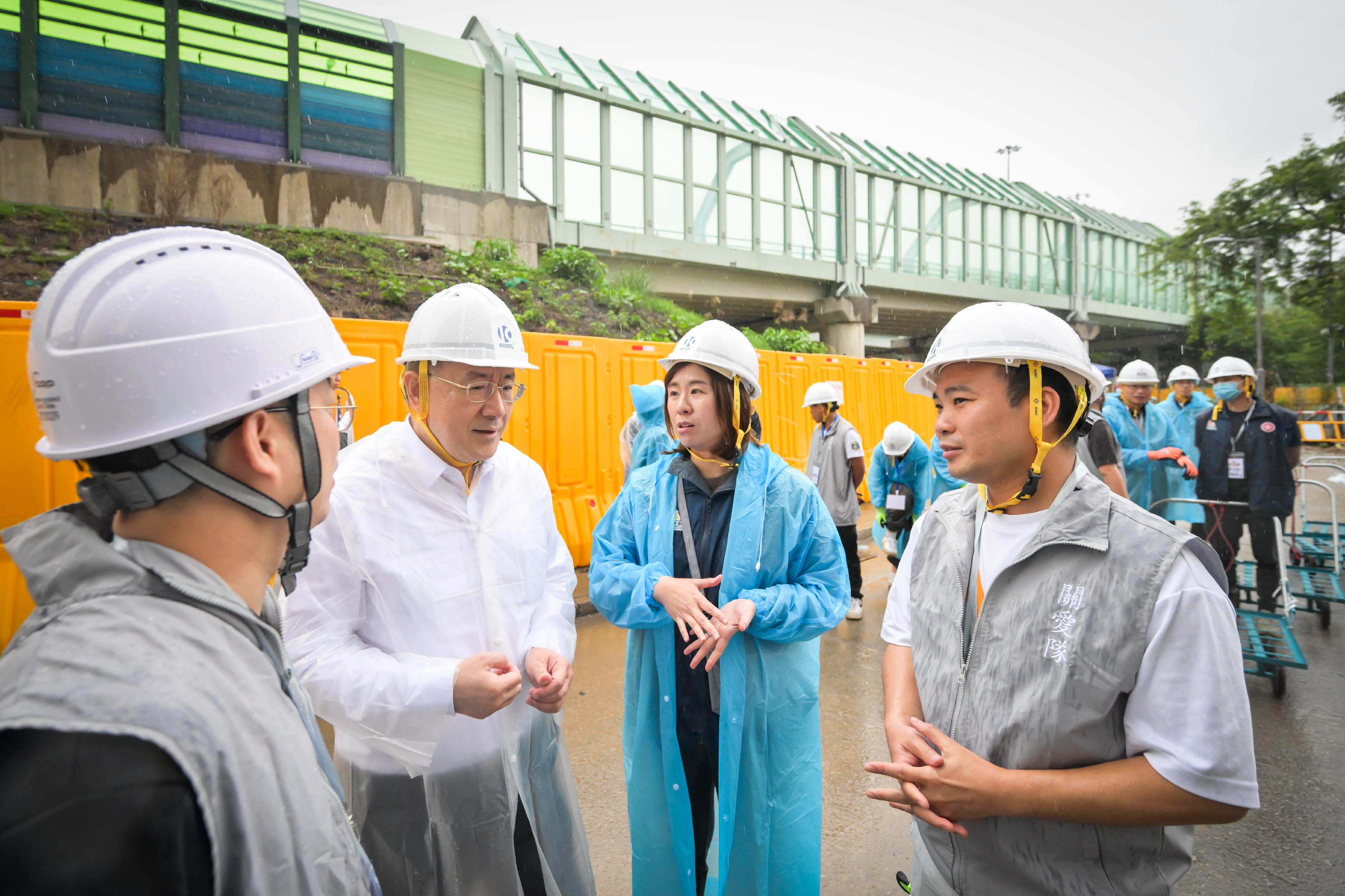 政務司副司長卓永興今日（四月二十四日）到大埔宏福苑，視察第二輪上樓安排同時開放兩幢樓宇的運作情況，以及雨天下的操作。卓永興先巡視在大埔浸信會公立學校設立的住戶等候區了解民政事務總署為等候居民提供的支援及安排預約車輛的服務；及後到物品儲存區了解同時開放兩幢樓宇後物品暫存服務的使用情況。其後，卓永興由民政事務總署副署長王婉蓉和大埔警區指揮官江永祥陪同，到宏昌閣一帶視察警務人員、民眾安全服務隊隊員和動員公務員聯同地區服務及關愛隊伍義工，同心協助居民搬運物品的工作。卓永興感謝所有參與支援工作的人員，大家積極熱心，願意多行一步，令上樓安排得以順利進行。圖示卓永興（左二）向地區服務及關愛隊伍義工了解工作的情況。旁為王婉蓉（右二）。