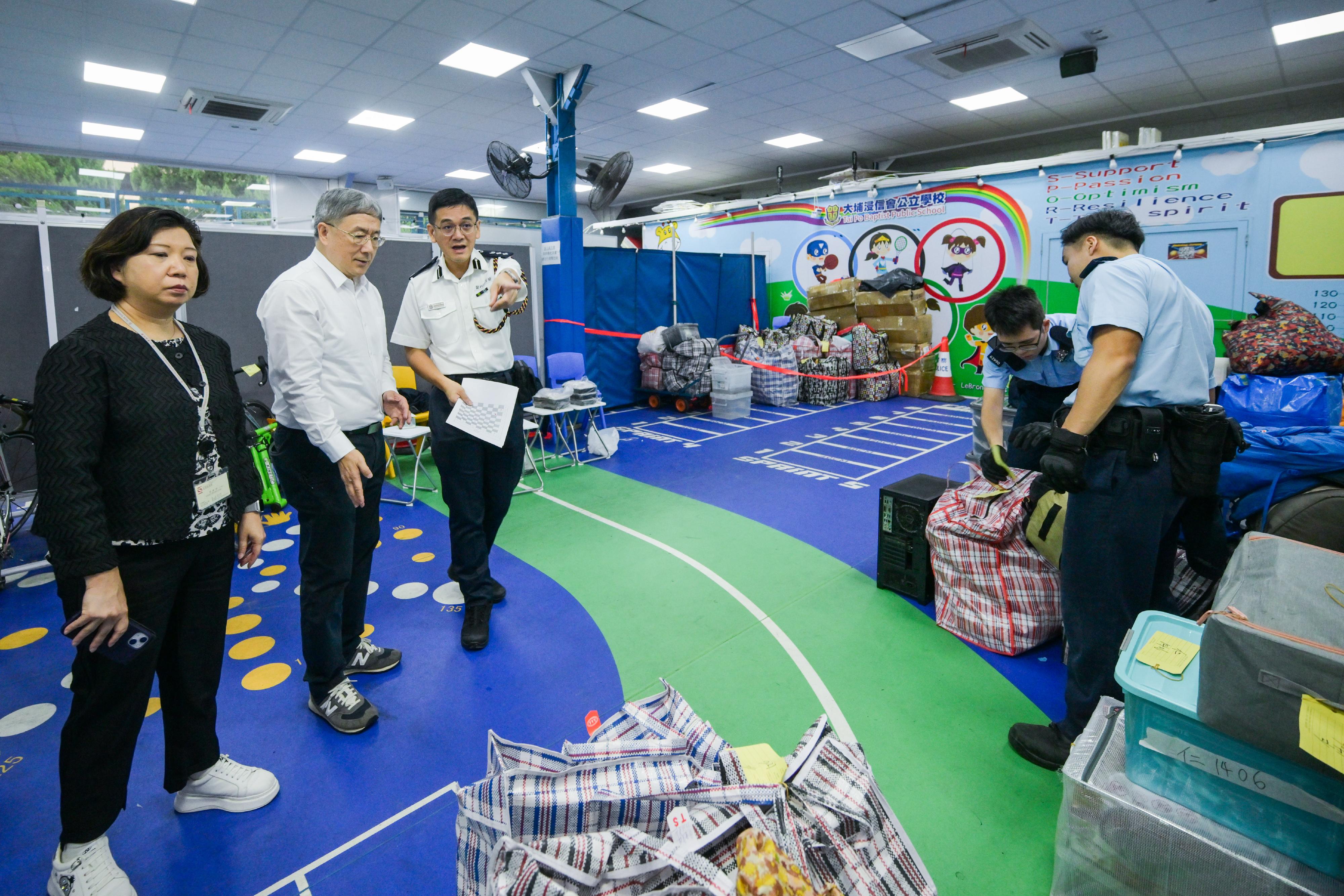The Deputy Chief Secretary for Administration, Mr Cheuk Wing-hing, conducted a site visit to Wang Fuk Court in Tai Po today (April 24) to inspect the second round of arrangements for the opening of two buildings in parallel, as well as the wet weather operations. Mr Cheuk first observed the resident waiting area set up at Tai Po Baptist Public School to learn about the support that the Home Affairs Department provided to residents waiting to return to their units, and the arrangements of a vehicle-booking service. Later he visited the on-site storage area to gain an understanding of the utilisation situation of the temporary storage service after opening two buildings at the same time. Subsequently, accompanied by Deputy Director of Home Affairs Ms Belinda Wong and the District Commander of Tai Po District, Mr Kong Wing-cheung, Mr Cheuk observed police officers, Civil Aid Service members, and mobilised civil servants, along with District Services and Community Care Team volunteers, working together to assist residents in transporting their belongings in the vicinity of Wang Cheong House. Mr Cheuk thanked all those involved in the support service for their enthusiasm and willingness to go the extra mile, ensuring the smooth progress of the access arrangements. Photo shows Mr Cheuk (second left) being briefed by Mr Kong (third left) on the utilisation situation of the storage area.