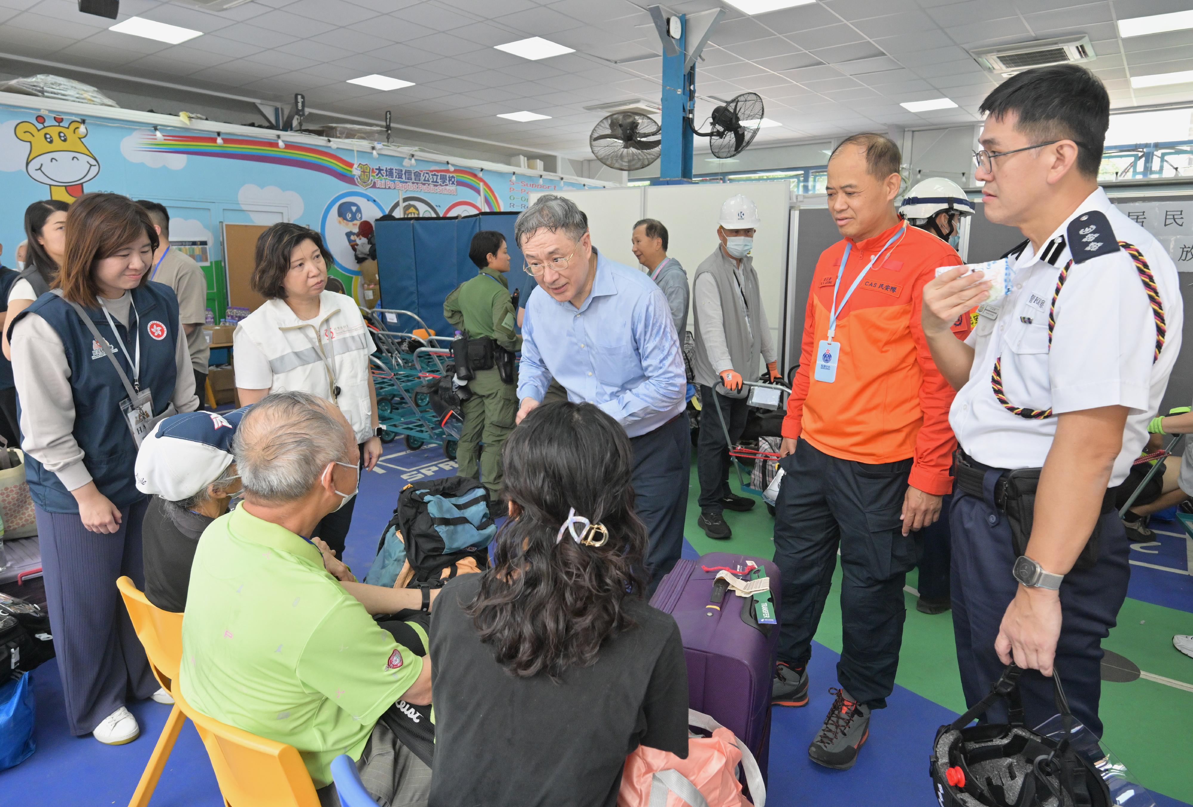 The Deputy Chief Secretary for Administration, Mr Cheuk Wing-hing, today (April 25) visited the resident waiting area set up at Tai Po Baptist Public School and talked with residents of Wang Yan House. They are thankful to staff who were helpful in transporting their belongings. Photo shows Mr Cheuk (centre) talking with members of a Wang Yan House household who are waiting there.