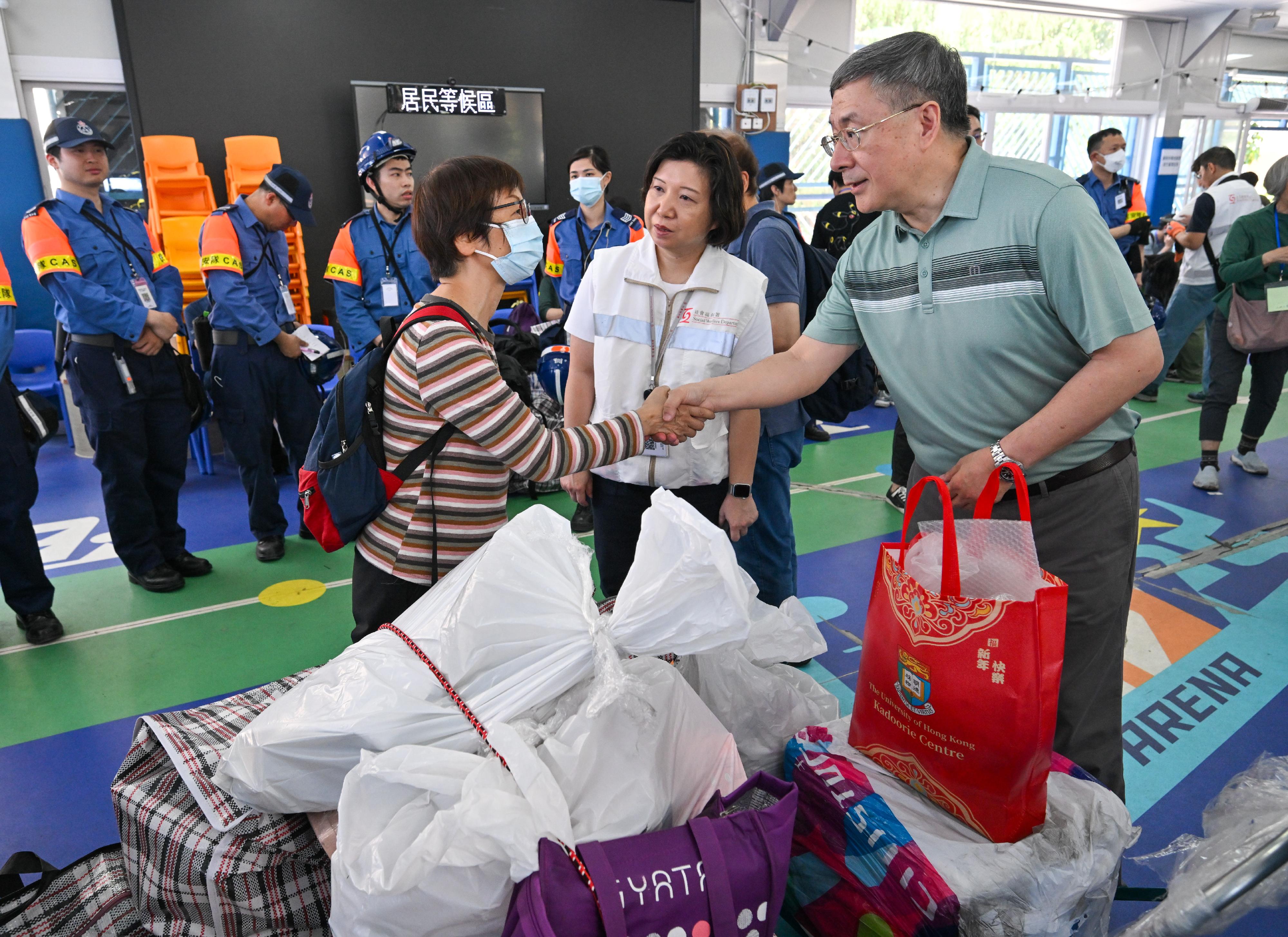 The Deputy Chief Secretary for Administration, Mr Cheuk Wing-hing, today (April 26) visited the resident waiting area set up at Tai Po Baptist Public School and talked with residents of Wang Tao House. They are thankful to staff who were helpful in transporting their belongings. Photo shows Mr Cheuk (right) shaking hands with a resident of Wang Tao House who is waiting there. 