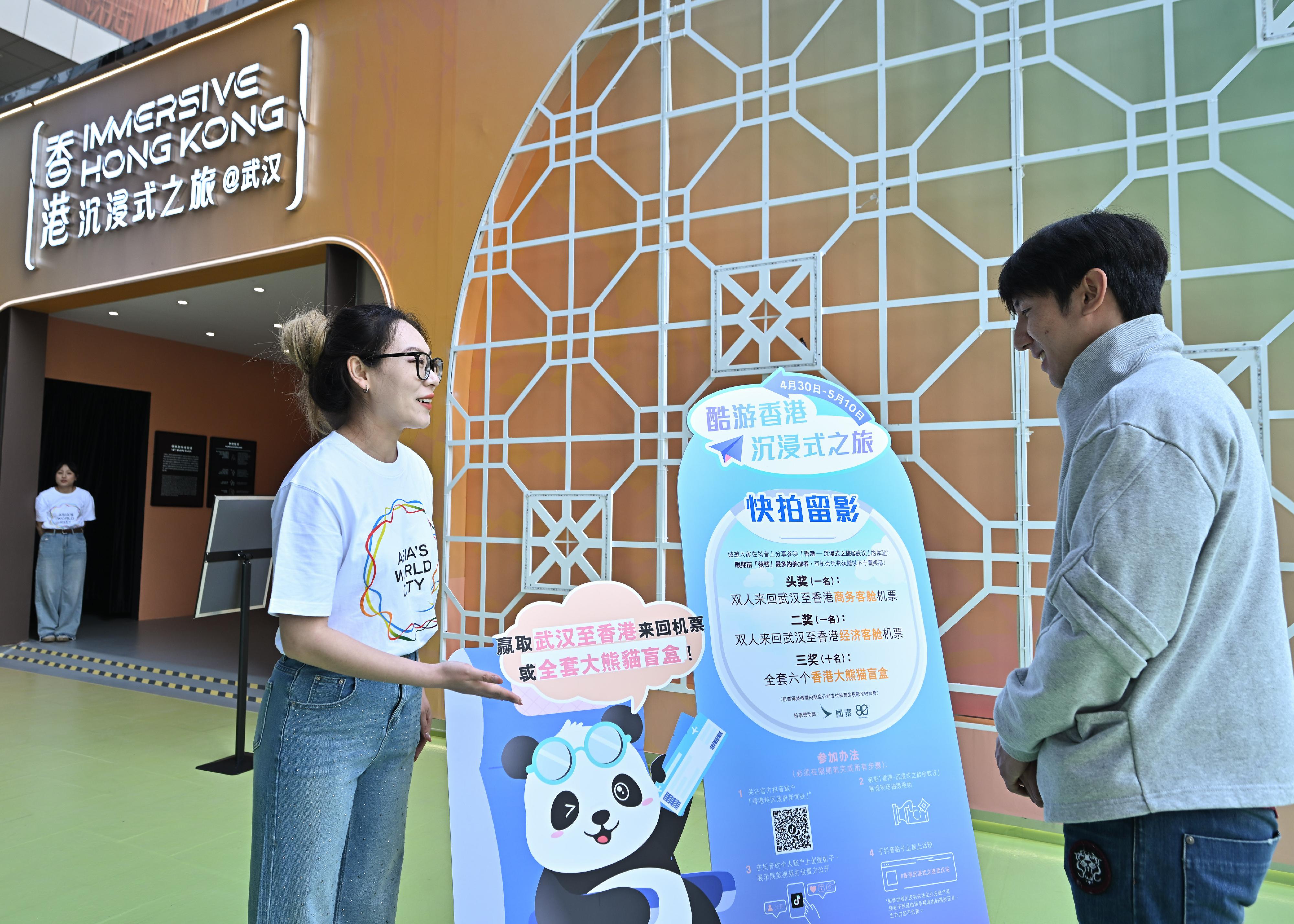The "Immersive Hong Kong" roving exhibition, which showcases the diversity and latest developments of Hong Kong through interactive art technology, opened in Wuhan, Hubei Province, today (April 30). The exhibition invites visitors from Wuhan and across Hubei Province to explore the unique opportunities and potential for tourism, education, business and investment in Hong Kong. An interactive game, "Snap a cool shot @Immersive Hong Kong", is taking place at the exhibition, with round-trip air tickets sponsored by Cathay Pacific as prizes. Photo shows visitors learning about the game.