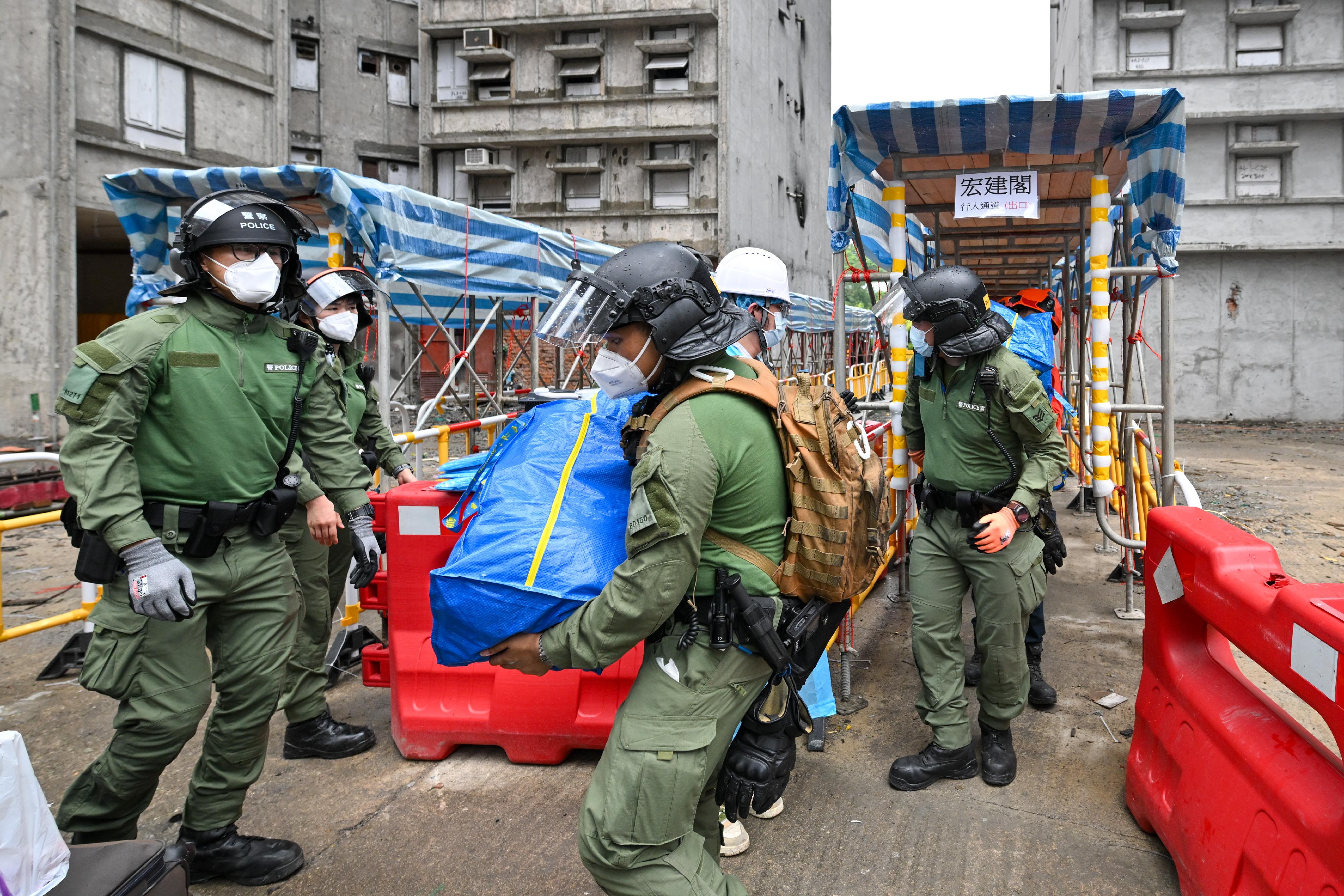 Police officers and members of the Civil Aid Service work together to help residents returning to their units move their belongings.