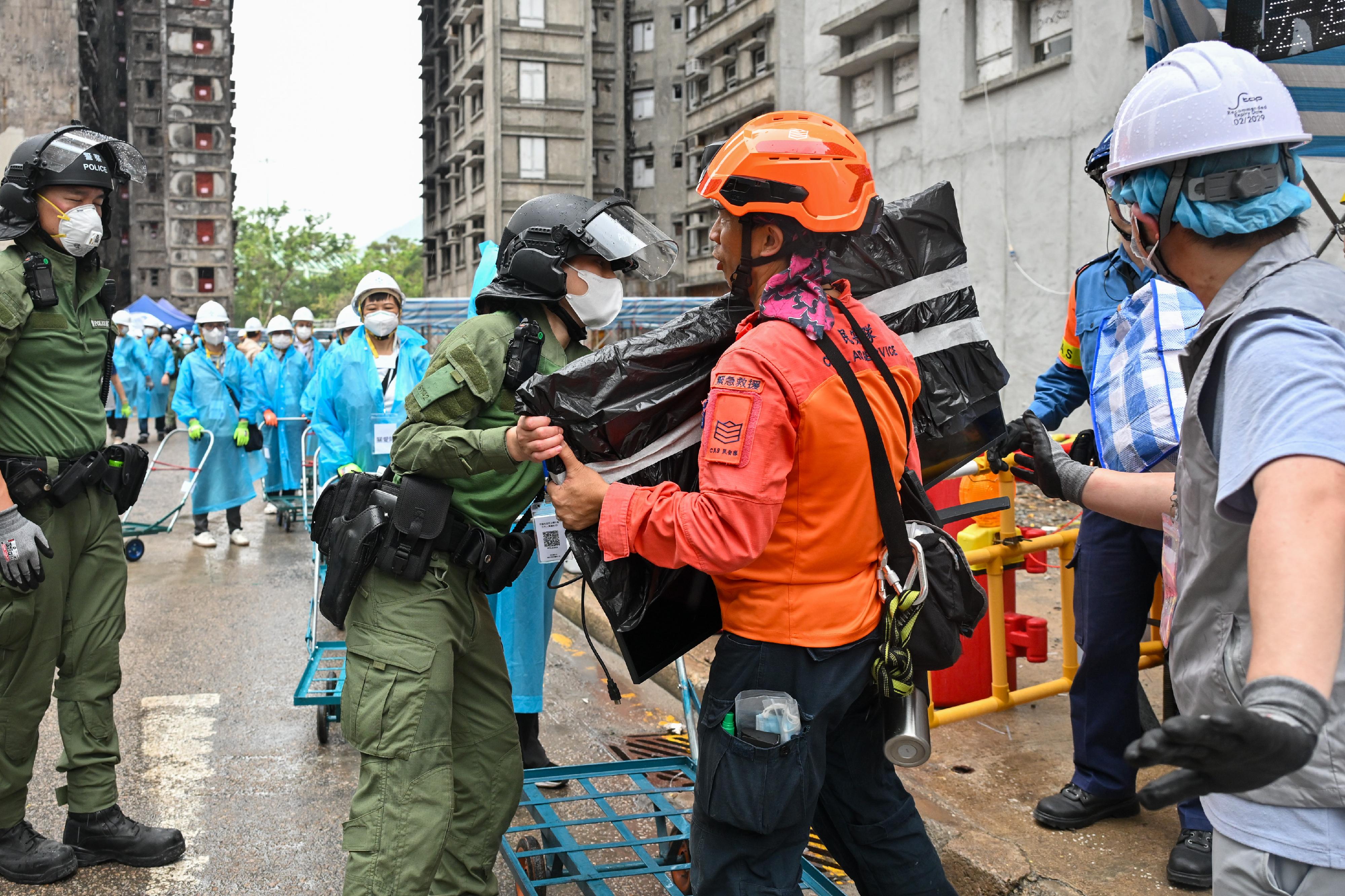 Police officers and members of the Civil Aid Service, together with volunteers from the District Services and Community Care Teams, work together to help residents returning to their units move their belongings.
