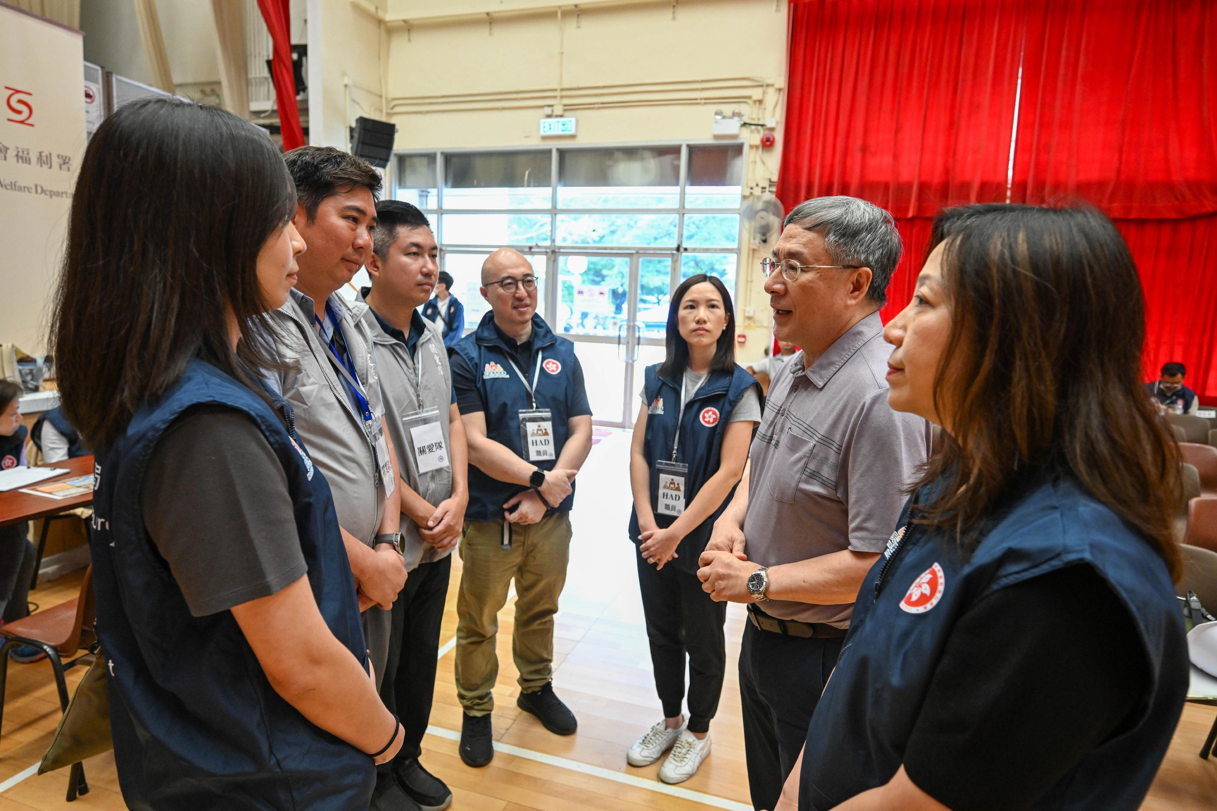 The Deputy Chief Secretary for Administration, Mr Cheuk Wing-hing, today (May 1) visited Kwong Fuk Community Hall in Tai Po to meet with colleagues of the Home Affairs Department (HAD) responsible for the operation of the registration centre and volunteers from the District Services and Community Care Teams. Mr Cheuk thanked the HAD colleagues and Care Teams volunteers for their good efforts. They have done a good job in venue management and item supplies, as well as helping residents move their belongings, fully embodying the "We Care We Serve" spirit of serving the community. Mr Cheuk encouraged the HAD staff and Care Teams volunteers to continue their efforts in fully supporting residents returning to their units. Photo shows Mr Cheuk (second right) talking with the HAD staff and Care Teams volunteers in the registration centre. Looking on is the Director of Home Affairs, Ms Priscilla To (first right).
