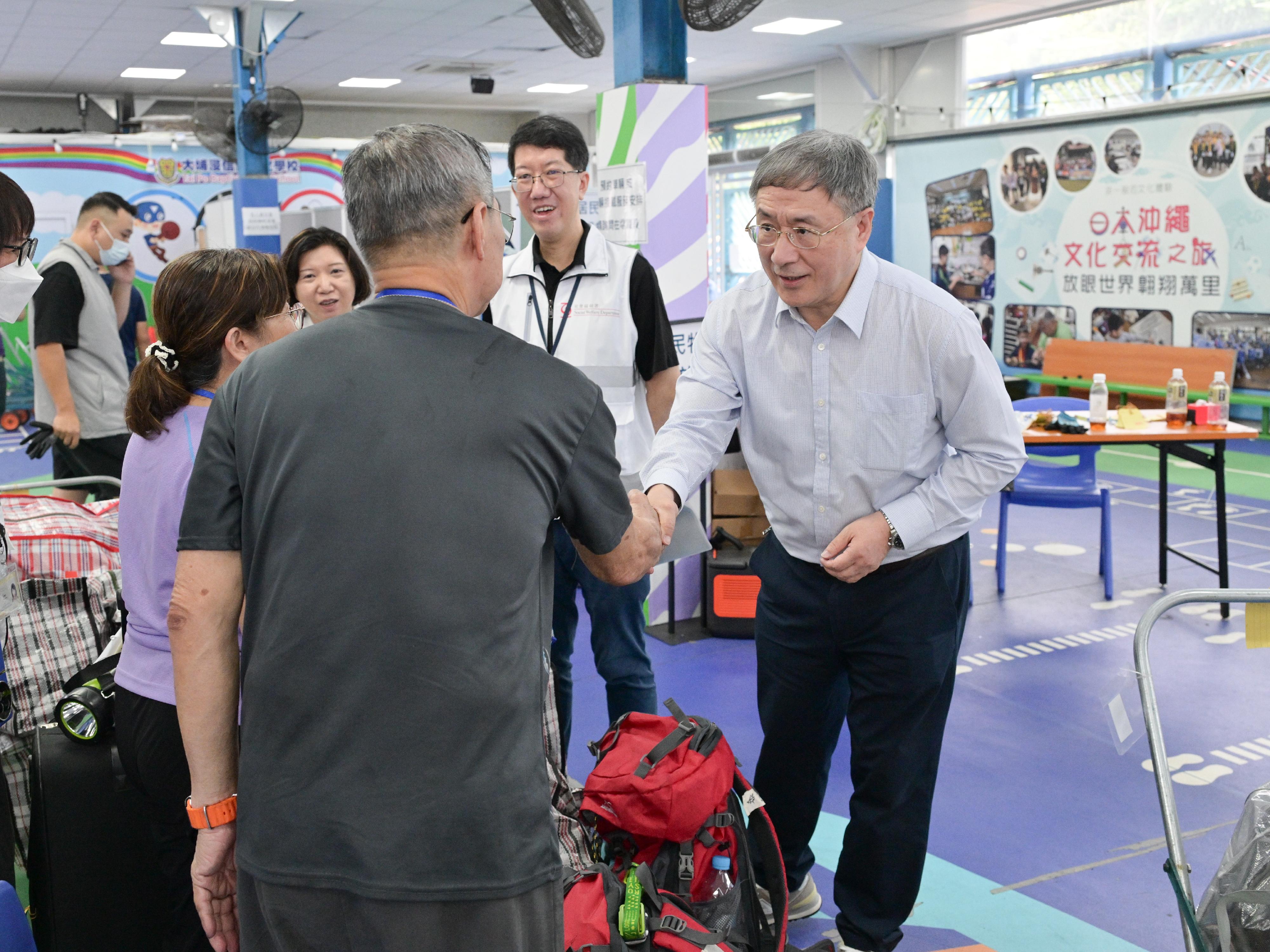 政務司副司長卓永興今日（五月三日）巡視大埔浸信會公立學校內的住戶等候區，與正在等候搬運物品上車的宏泰閣居民交談。圖示卓永興（右）與居民握手。
