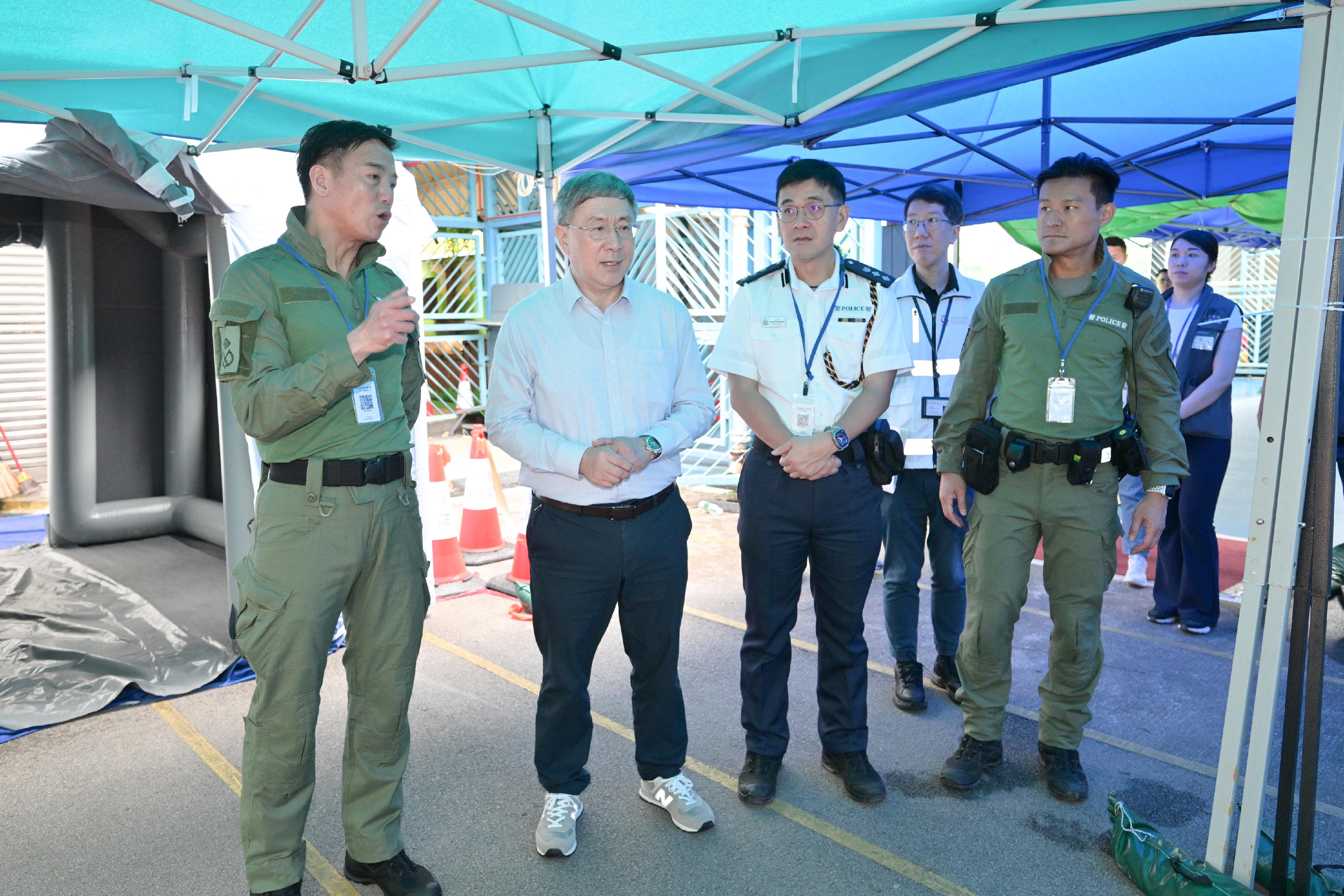 The Deputy Chief Secretary for Administration, Mr Cheuk Wing-hing, today (May 3) inspected the arrangements for residents of Wang Fuk Court in Tai Po returning to their units. Photo shows Mr Cheuk (second left) being briefed by the Director of Operations of Hong Kong Police Force, Mr Lui Kam-ho (first left), on using additional marquees to create a covered pedestrian walkway to provide shelter from the rain and facilitate residents in transporting their belongings to the vehicles.