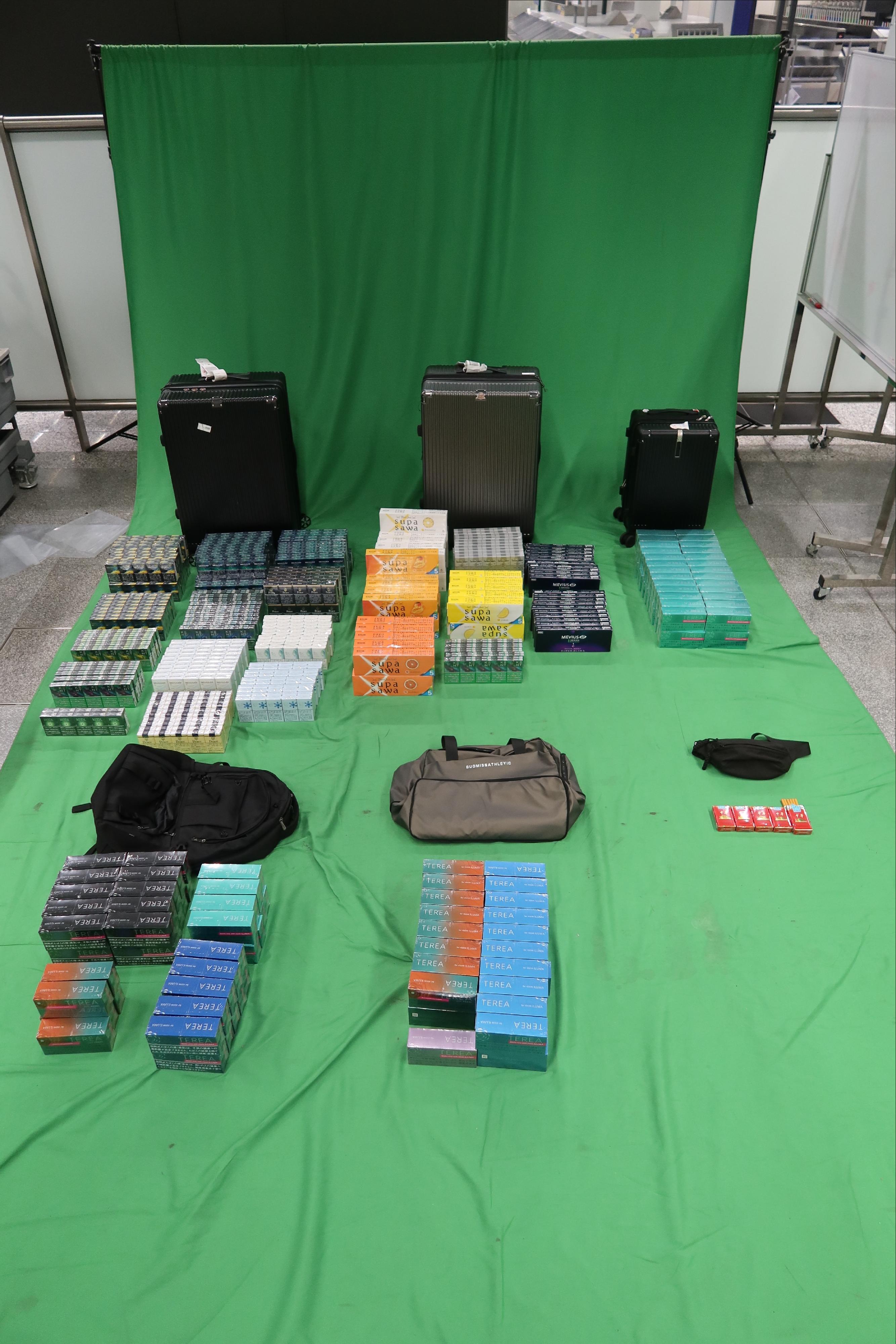 Three incoming passengers were sentenced to between three to six months' imprisonment and fined $1,000 by the West Kowloon Magistrates' Courts yesterday (May 4) and today (May 5) for importing duty-not-paid cigarettes and failing to declare them to Customs officers, as well as for importing alternative smoking products, in contravention of the Dutiable Commodities Ordinance and the Import and Export Ordinance. Photo shows the duty-not-paid cigarettes and the alternative smoking products seized from the personal baggage of the 38-year-old incoming male passenger.