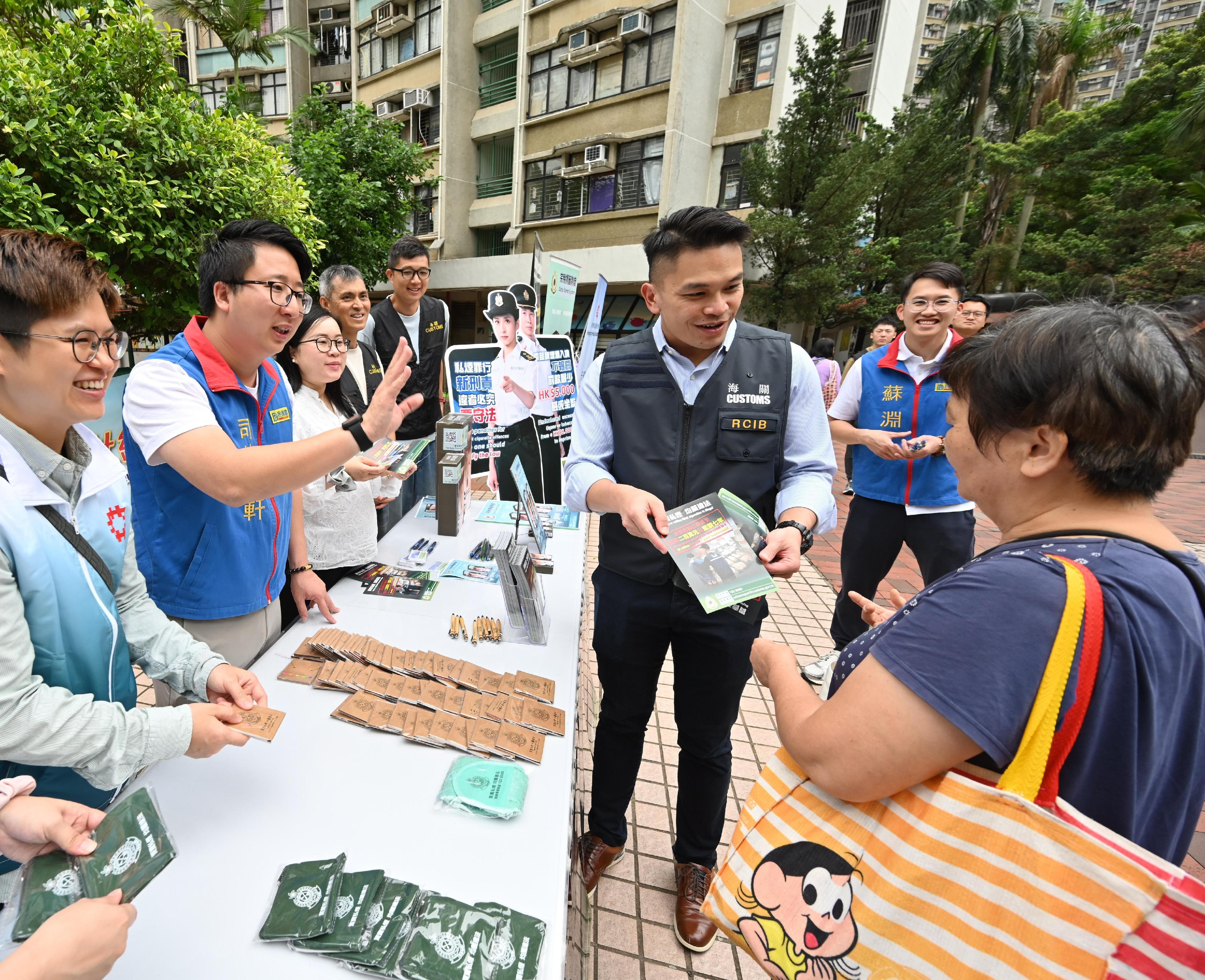 Hong Kong Customs conducted joint anti-illicit cigarette publicity activities with members of the District Council, the Tobacco and Alcohol Control Office of the Department of Health, the Hong Kong Police Force and the Housing Department in Tin Tsz Estate, Tin Yiu Estate, and Tin Shui Estate in Tin Shui Wai today (May 6). Customs also publicised the Duty Stamp System. Photo shows a Customs officer explaining anti-illicit cigarette messages to a resident.