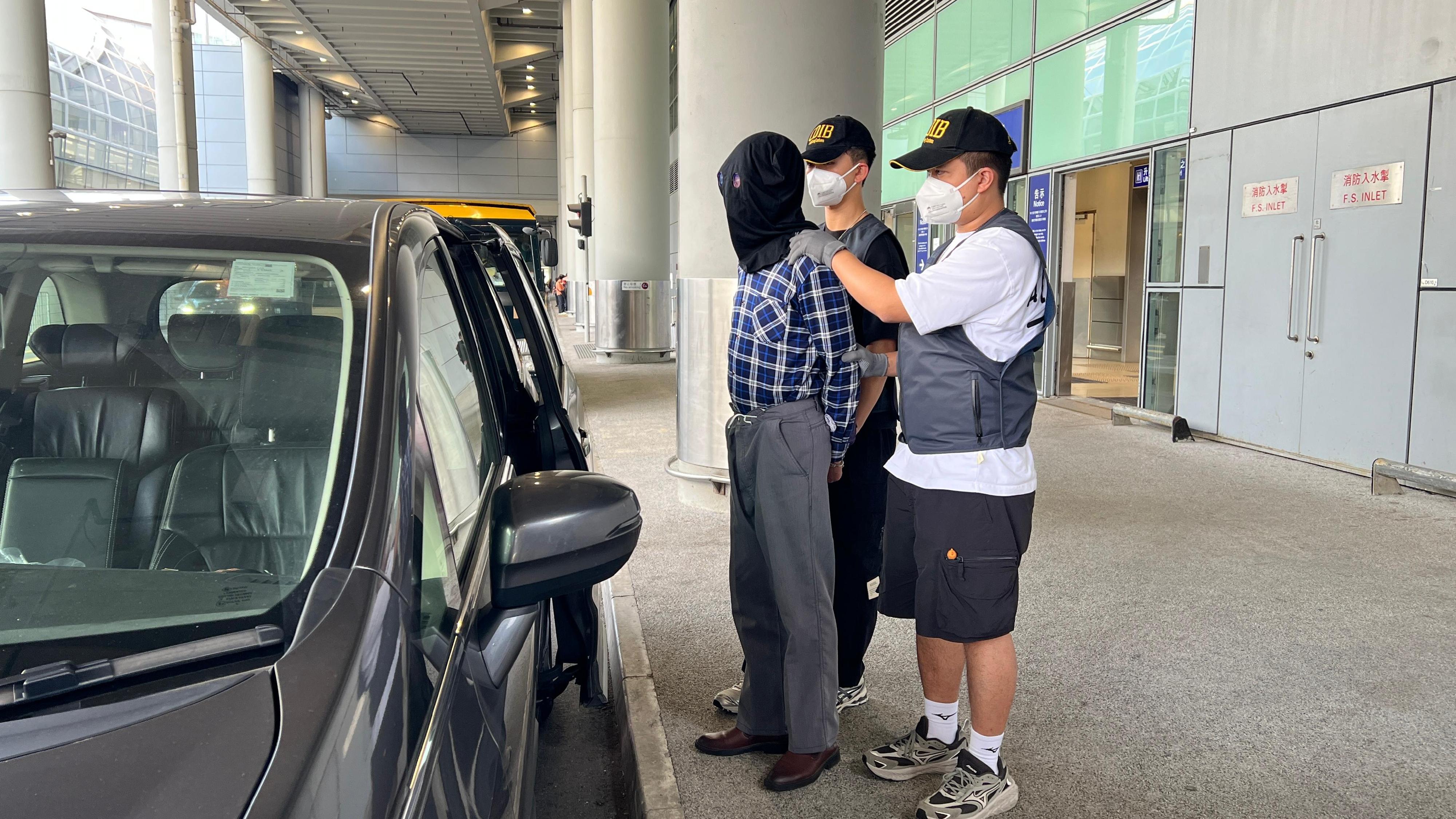香港海關昨日(五月九日)在香港國際機場偵破一宗旅客販運毒品的案件,共檢獲約二點二五公斤懷疑海洛英、四粒懷疑威而鋼及二十六枝未完稅香煙,估計市值共約一百四十萬元。圖示涉案的被捕人士(左一)。