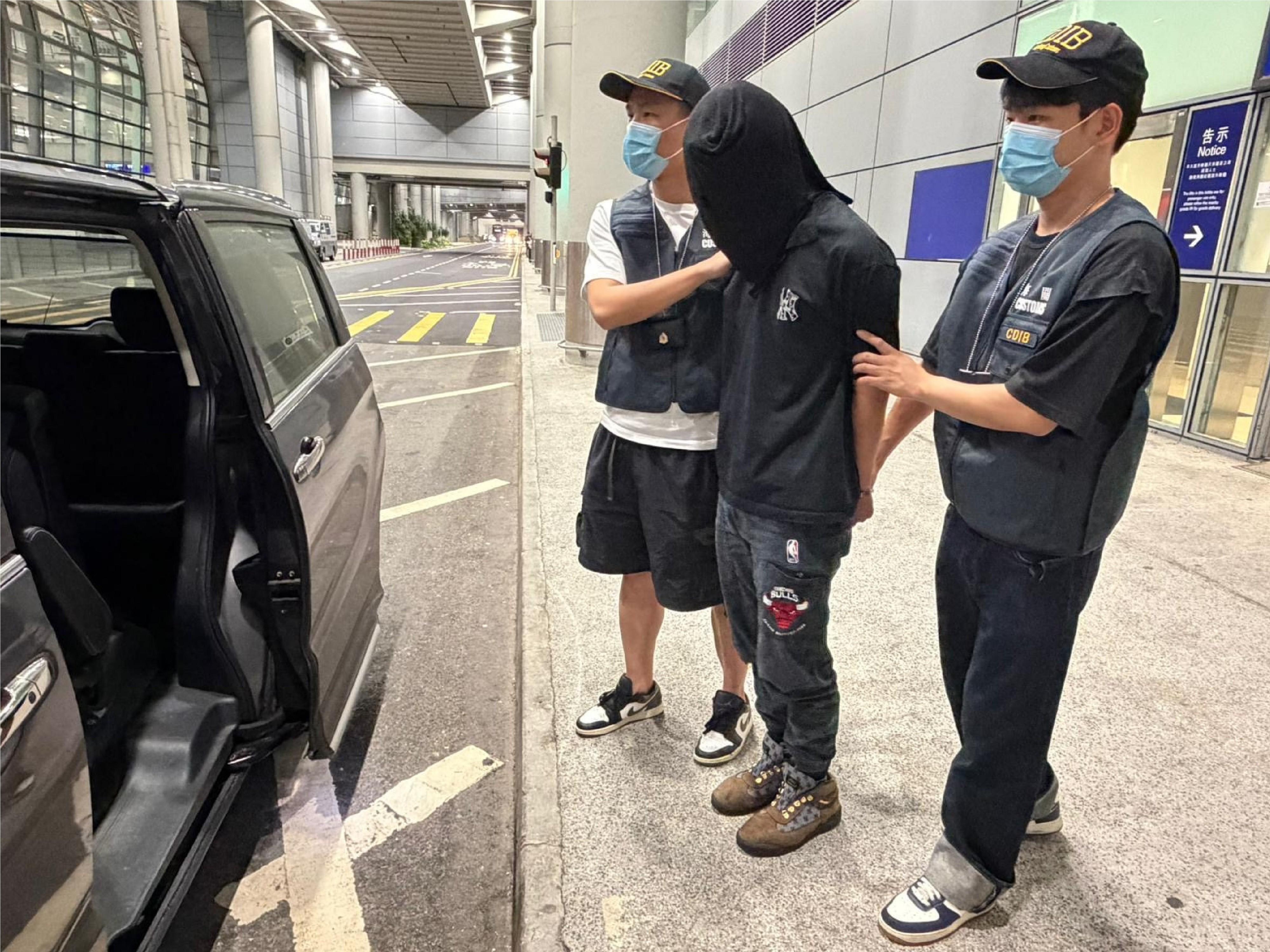 香港海關於五月七日在香港國際機場偵破一宗空運包裹販運毒品案件,檢獲約十一公斤懷疑氯胺酮,估計市值約四百三十萬元。圖示涉案的被捕人士(中)。