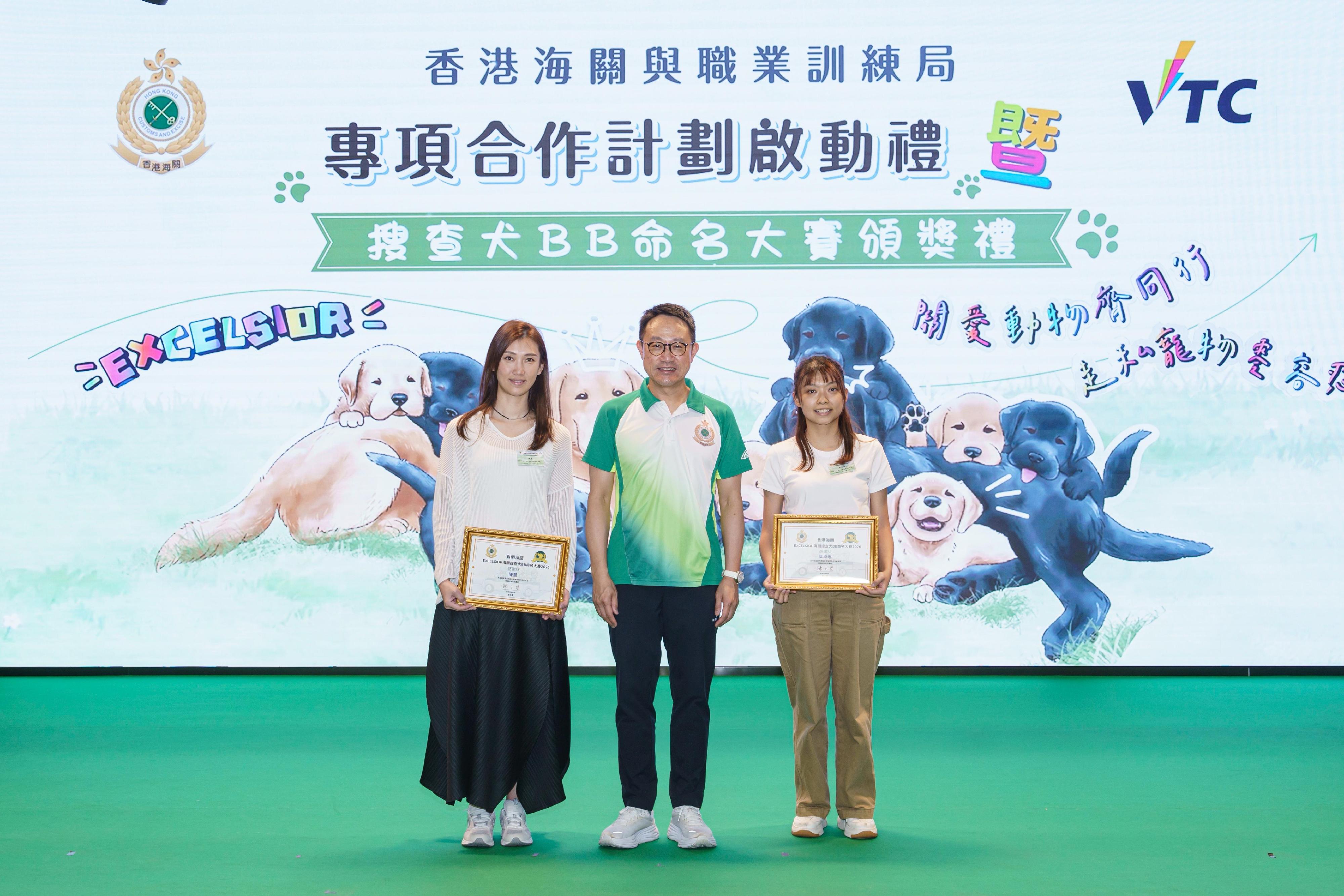 Hong Kong Customs and the Vocational Training Council (VTC) today (May 16) held a launch ceremony for Hong Kong Customs and VTC cooperation plan and prize presentation for a puppy-naming competition at the Hong Kong Institute of Vocational Education (Kwai Chung). Photo shows the Commissioner of Customs and Excise, Mr Chan Tsz-tat (centre), and two students from the VTC Design Discipline, who assisted Hong Kong Customs in designing postcards and souvenirs themed on Customs detector dog puppies "EXCELSIOR".
