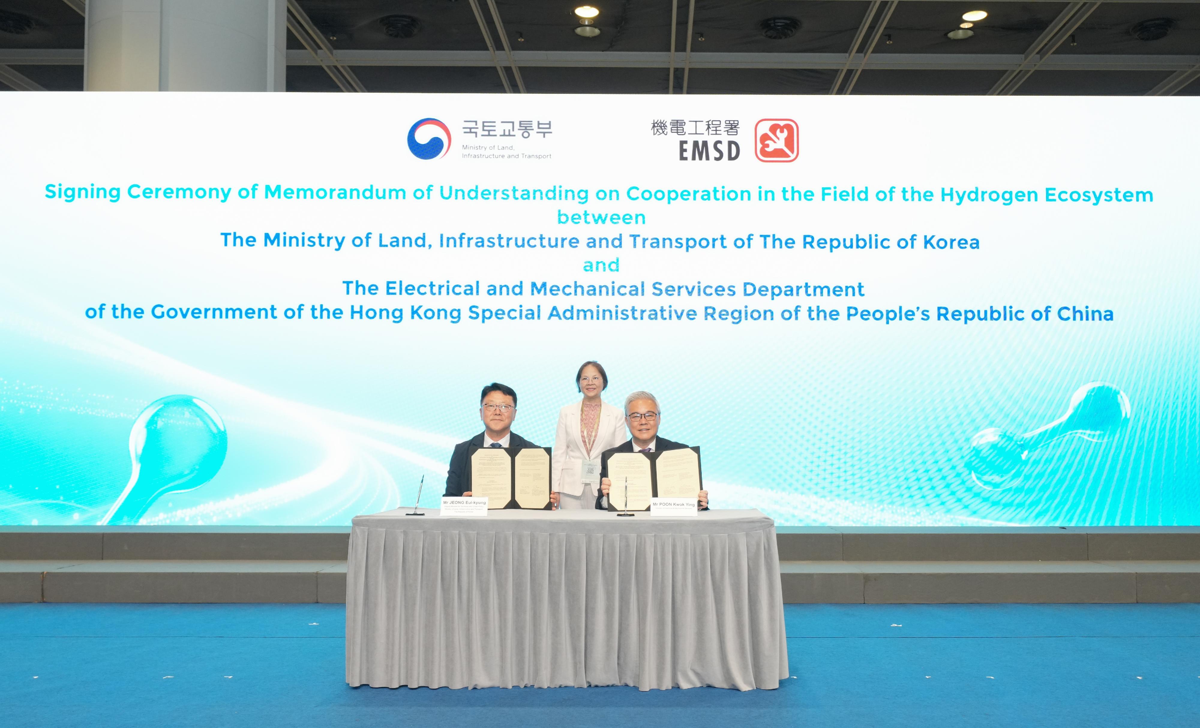 The opening ceremony of the International Hydrogen Development Symposium 2026 was held at the Hong Kong Convention and Exhibition Centre today (May 18). Photo shows the Director of Electrical and Mechanical Services, Mr Poon Kwok-ying (right), and the Deputy Minister for Territorial and Urban Policy at the Ministry of Land, Infrastructure and Transport of the Republic of Korea, Mr Jeong Eui-kyung (left), signing a Memorandum of Understanding to promote the development of hydrogen ecosystems between the two places, witnessed by the Acting Secretary for Environment and Ecology, Miss Diane Wong (centre).