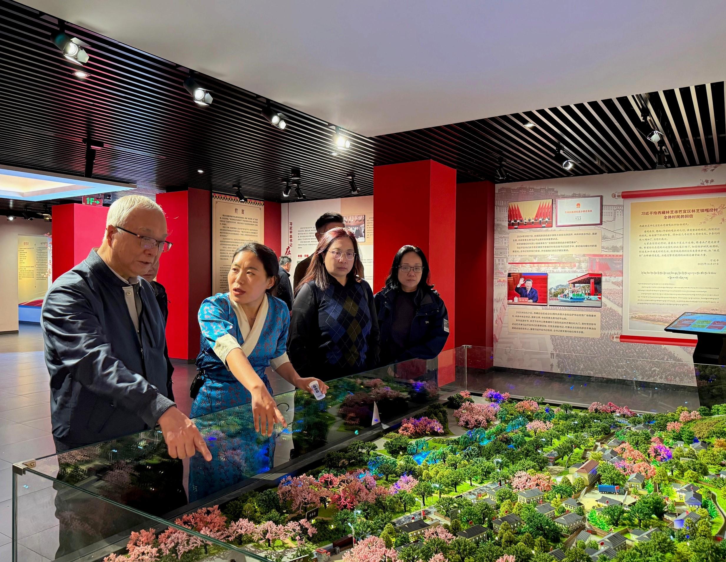 環境及生態局局長謝展寰昨日(五月十八日)展開西藏自治區訪問行程。圖示謝展寰(左一)、環境及生態局常任秘書長(食物)楊碧筠(右二)及食物環境衞生署食物安全中心食物安全專員黃宏醫生(右一)在林芝市嘎拉村聽取人員介紹當地發展鄉村生態旅遊包括水果種植採摘園的情況。