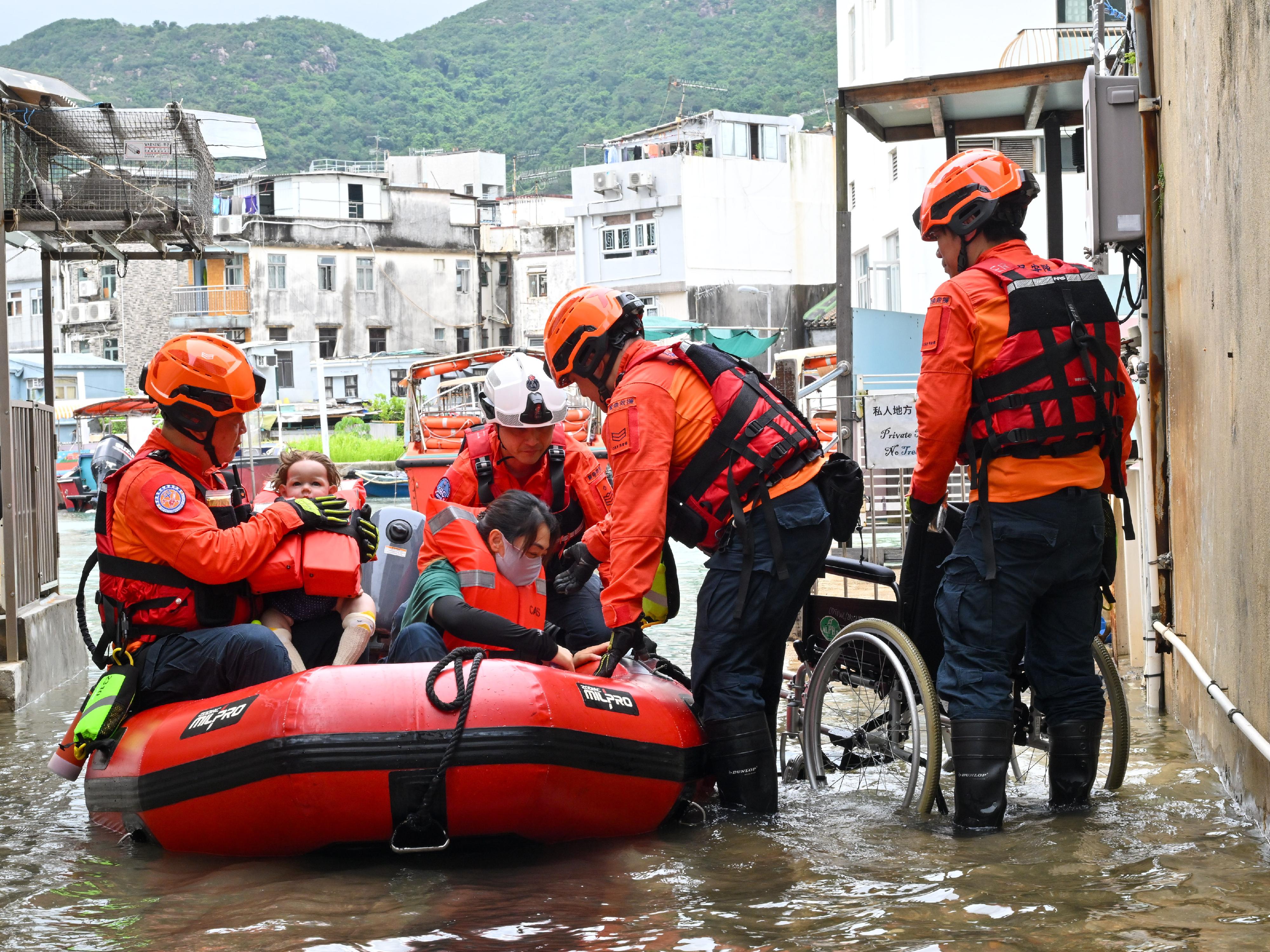 The Islands District Office conducted an interdepartmental rescue and evacuation drill in the event of flooding in Tai O today (May 20). Photo shows Civil Aid Service members rescuing trapped residents by an inflatable boat during the drill.