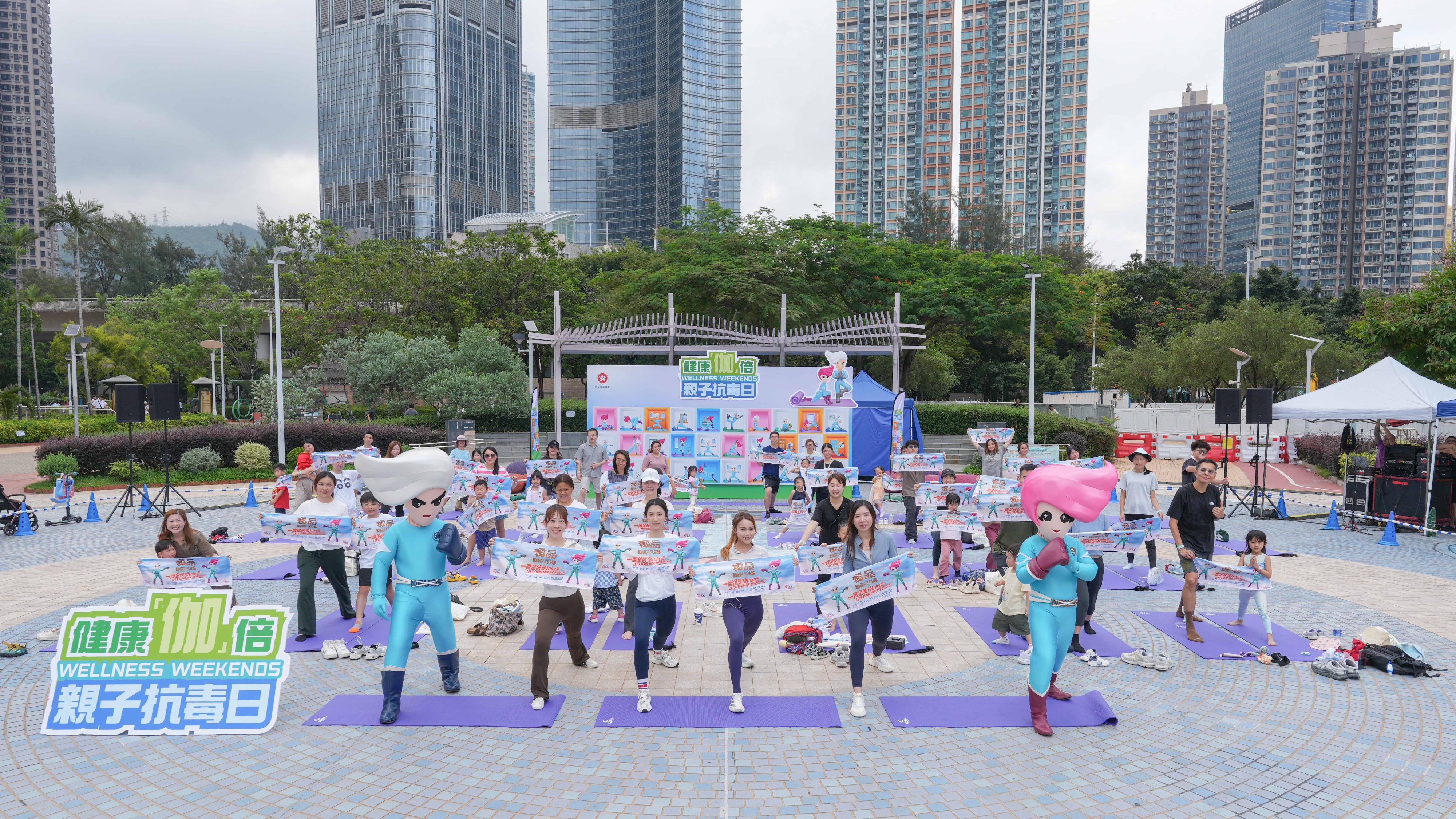 The "Wellness Weekends" organised by the Narcotics Division of the Security Bureau comprised three stops, with six family yoga workshops held in April and May at Kai Tak Station Square, Tamar Park and Tsuen Wan Park. Photo shows yoga tutor Sandy To (front row, third right) leading the participants in the yoga event at Tsuen Wan Park.