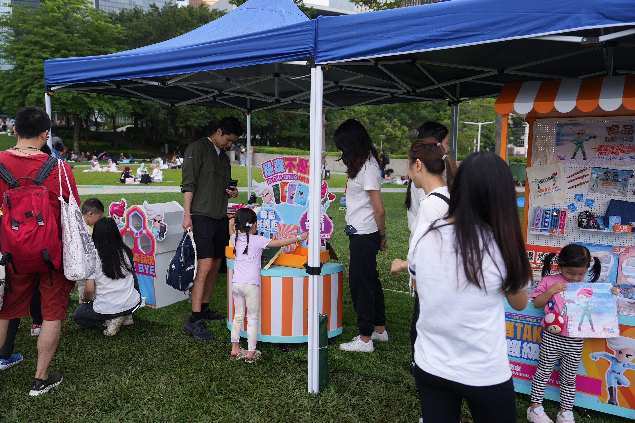 The "Wellness Weekends" organised by the Narcotics Division of the Security Bureau comprised three stops, with six family yoga workshops held in April and May at Kai Tak Station Square, Tamar Park and Tsuen Wan Park. Photo shows members of the public participating in the "Drug-free Camp" pop-up anti-drug game booth at Tamar Park.
