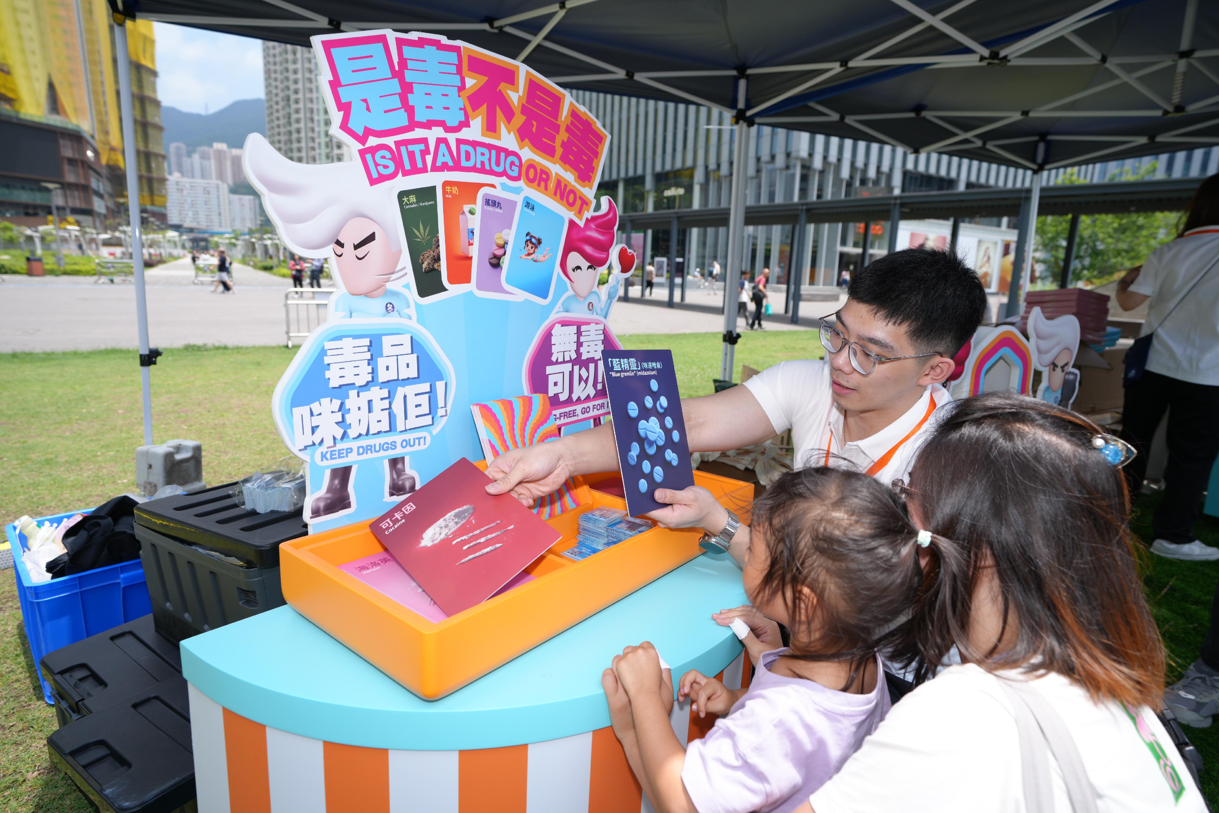 The "Wellness Weekends" organised by the Narcotics Division of the Security Bureau comprised three stops, with six family yoga workshops held in April and May at Kai Tak Station Square, Tamar Park and Tsuen Wan Park. Photo shows members of the public participating in the "Drug-free Camp" pop-up anti-drug game booth at Kai Tak Station Square.