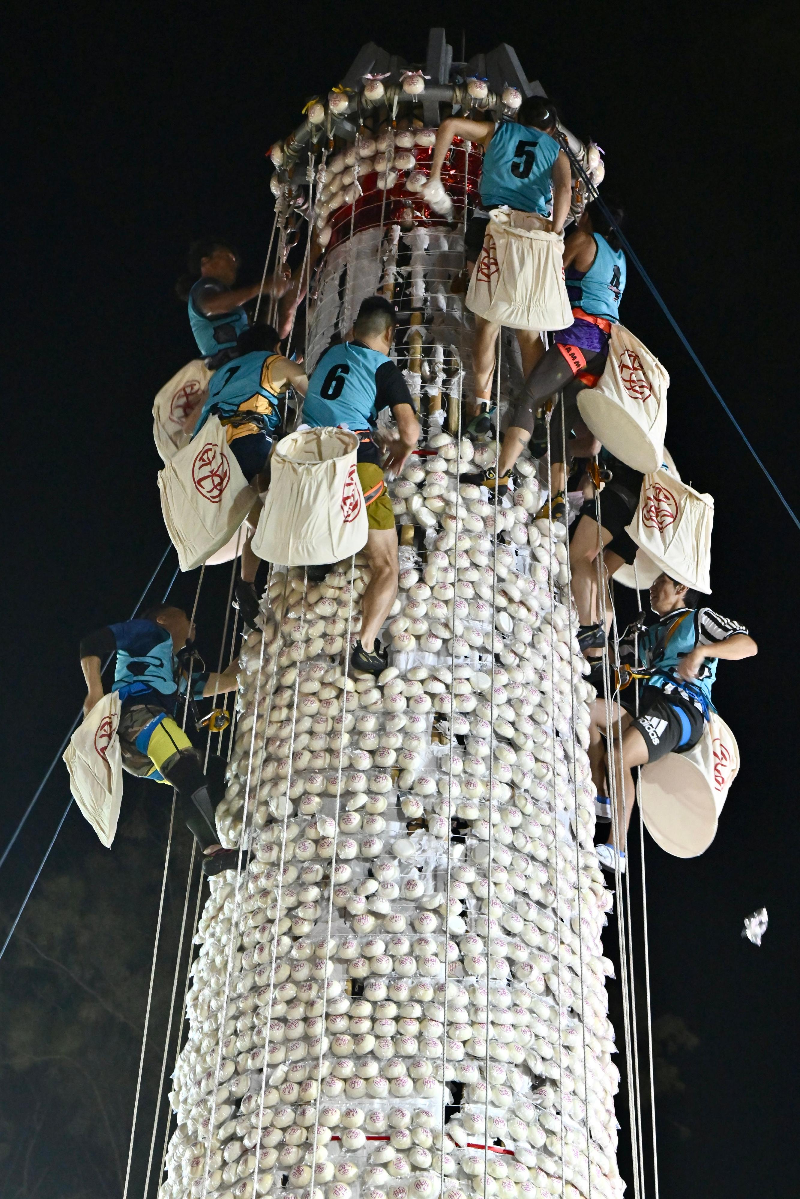 The Bun Scrambling Competition in Cheung Chau concluded early this morning (May 25). Photo shows the finalists scrambling up the bun tower to snatch as many buns as they can within a three-minute time limit to vie for the championships.