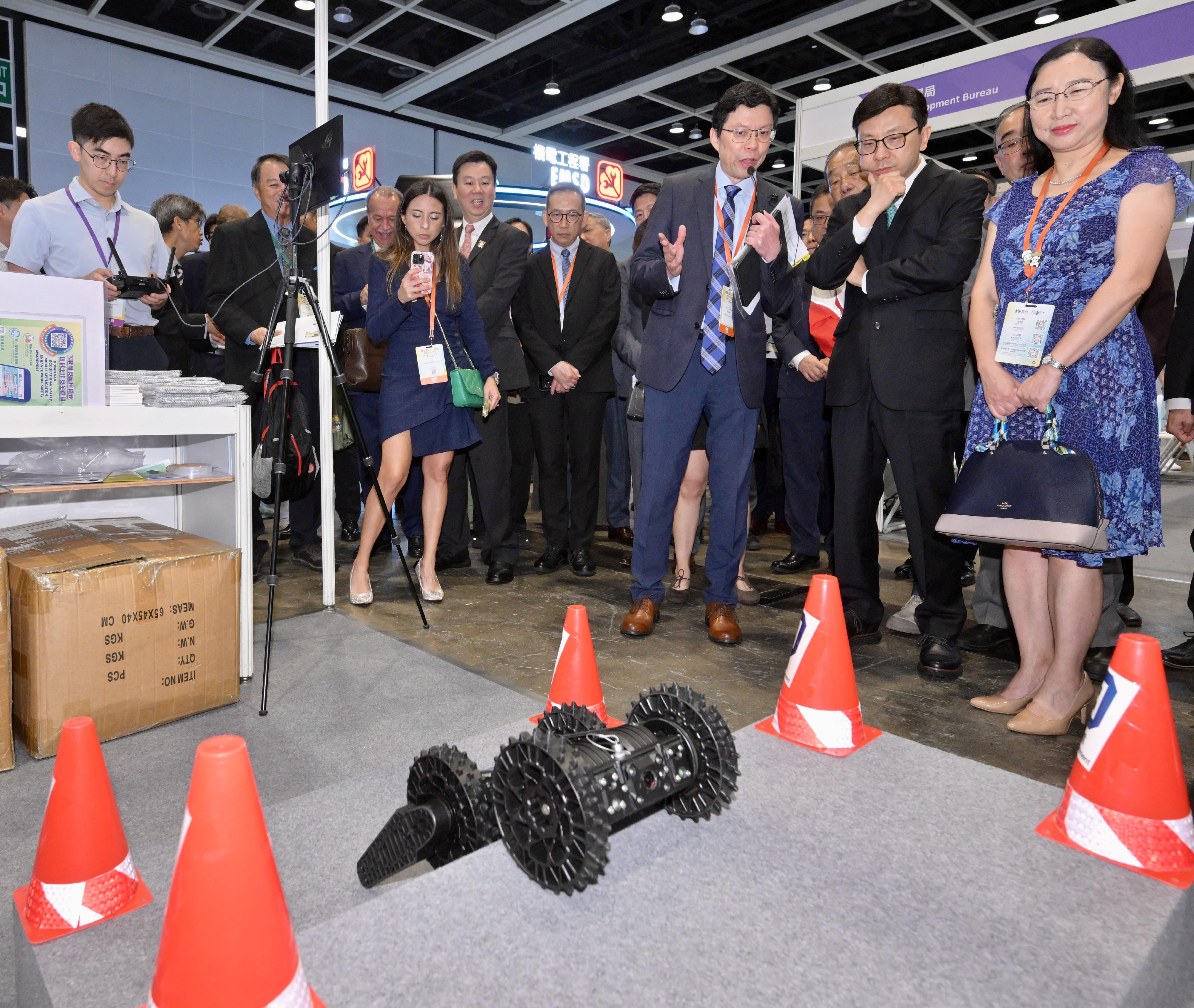 The OSH INNO Expo, jointly organised by the Labour Department (LD) and the Occupational Safety and Health Council, opened today (June 2). Photo shows the Secretary for Labour and Welfare, Mr Chris Sun (second right), the Permanent Secretary for Labour and Welfare, Ms Alice Lau (first right), and other guests visiting the LD's booth to learn how the department utilises small unmanned detection vehicles to assist in inspecting high-risk drainage works and investigating accidents.