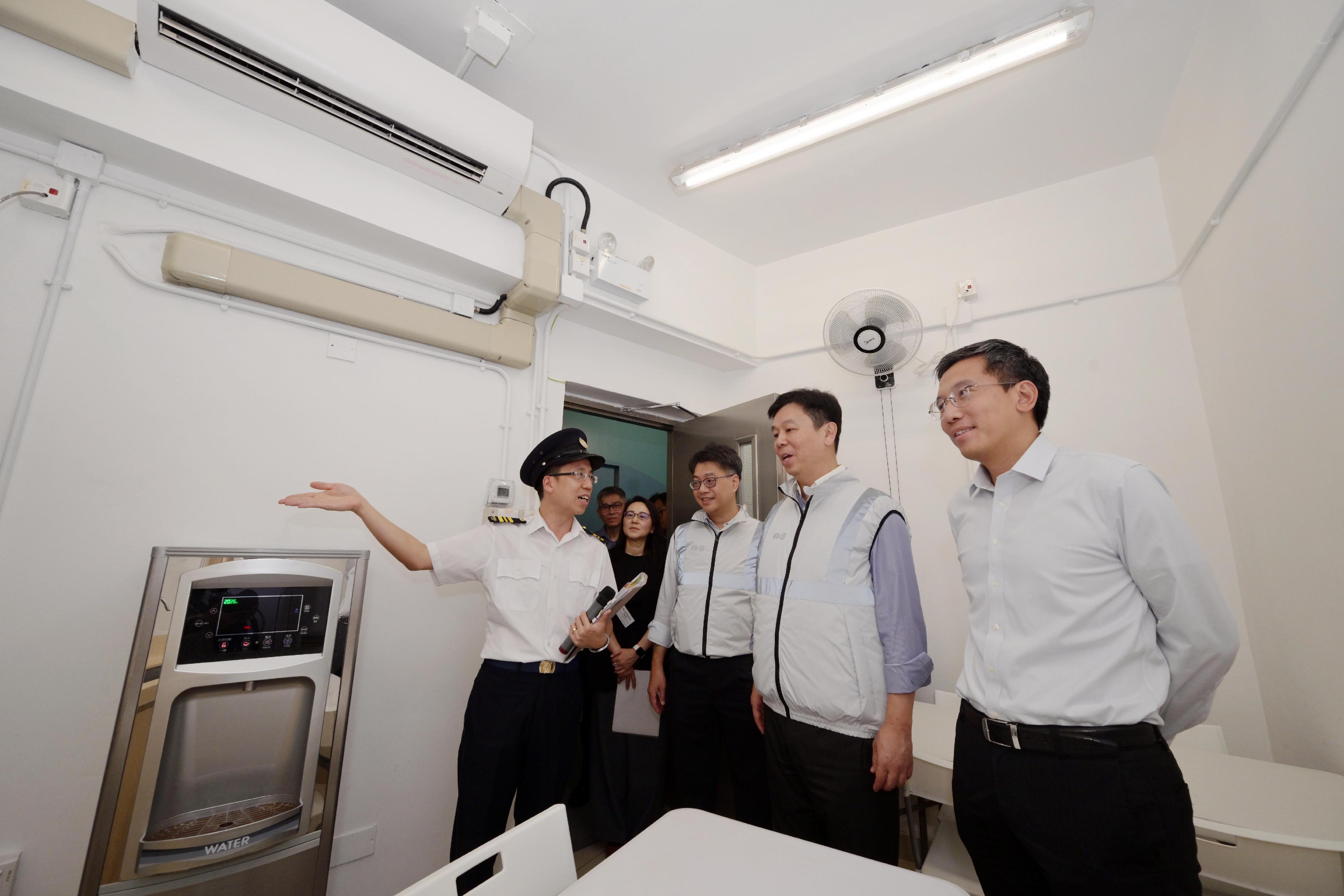 勞工處聯同食物環境衞生署代表今日(六月四日)到筲箕灣一個公眾垃圾收集站推廣預防工作時中暑及預先訂立惡劣天氣及極端情況下的工作安排。圖示勞工處副處長(職業安全及健康)馮浩賢(右二)和食物環境衞生署副署長(環境衞生)姚繼卓(右一)一同聽取人員講解為前線工人所設置的員工休息及用膳設施。