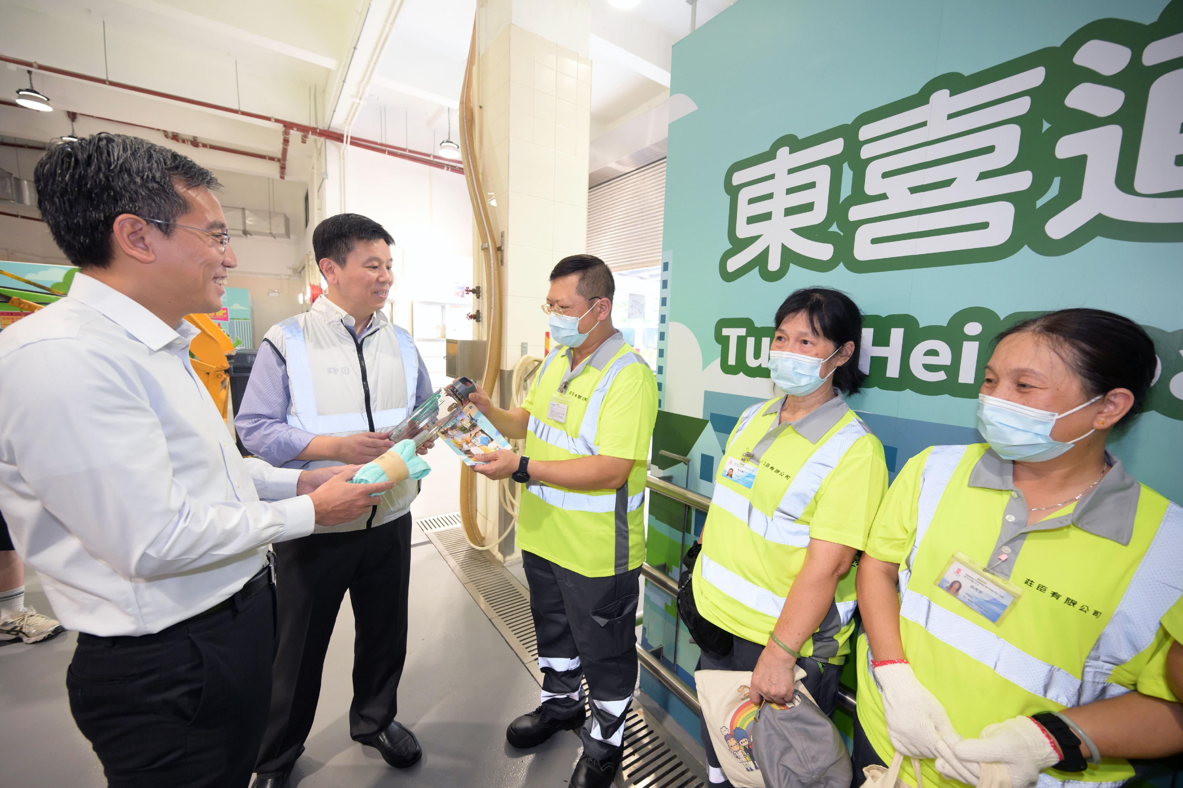 The Labour Department and representatives of the Food and Environmental Hygiene Department visited a public refuse collection point in Shau Kei Wan to promote the prevention of heat stroke at work and prior work arrangements in times of adverse weather and extreme conditions today (June 4). Photo shows the Deputy Commissioner for Labour (Occupational Safety and Health), Mr Vincent Fung (second left), and the Deputy Director of Food and Environmental Hygiene (Environmental Hygiene), Mr Arsene Yiu (first left), distributing cooling products to workers.