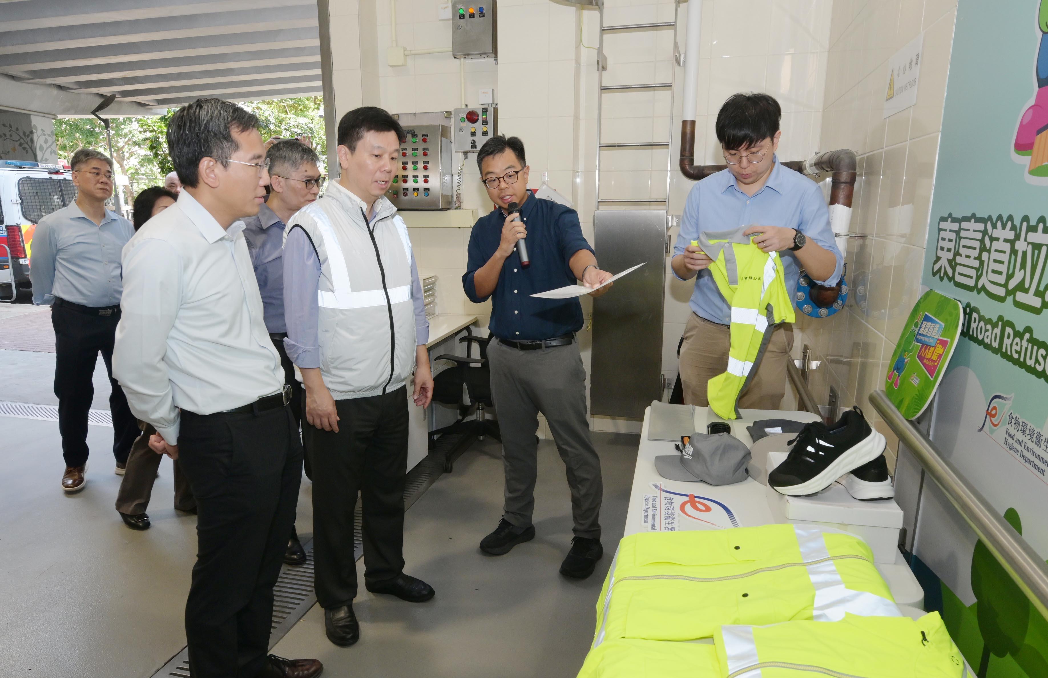 The Labour Department and representatives of the Food and Environmental Hygiene Department visited a public refuse collection point in Shau Kei Wan to promote the prevention of heat stroke at work and prior work arrangements in times of adverse weather and extreme conditions today (June 4). Photo shows the Deputy Commissioner for Labour (Occupational Safety and Health), Mr Vincent Fung (second left), and the Deputy Director of Food and Environmental Hygiene (Environmental Hygiene), Mr Arsene Yiu (first left), being briefed by staff on the various protective equipment provided to frontline cleansing workers.