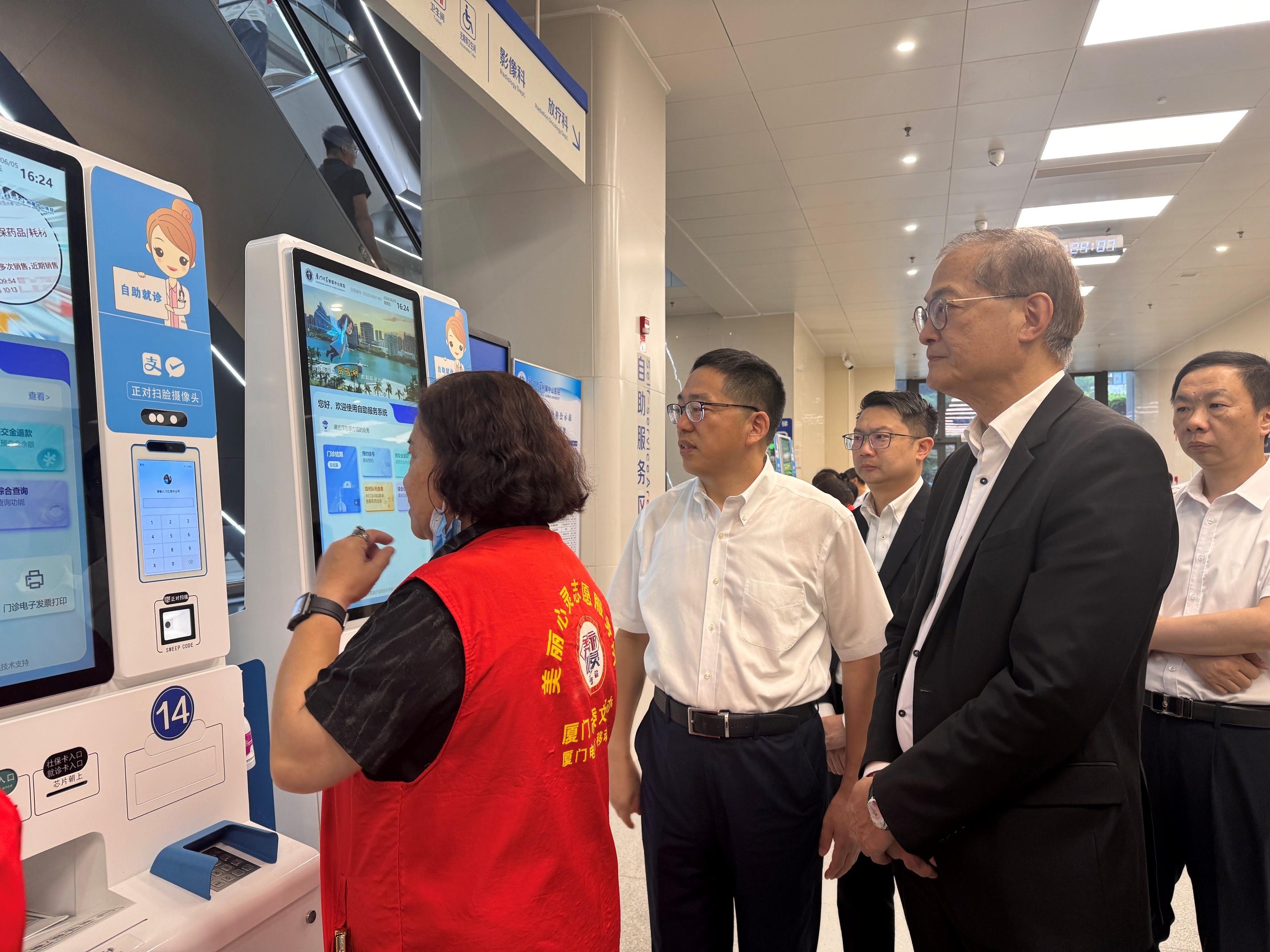 The Secretary for Health, Professor Lo Chung-mau, leads a delegation to visit Zhongshan Hospital Xiamen University in Xiamen today (June 5). Photo shows Professor Lo (second right) receiving a briefing by a hospital staff member on the automatic service system of the hospital. Also accompanying is the Senior Advisor (Secretary for Health's Office), Dr Joe Fan (third right).