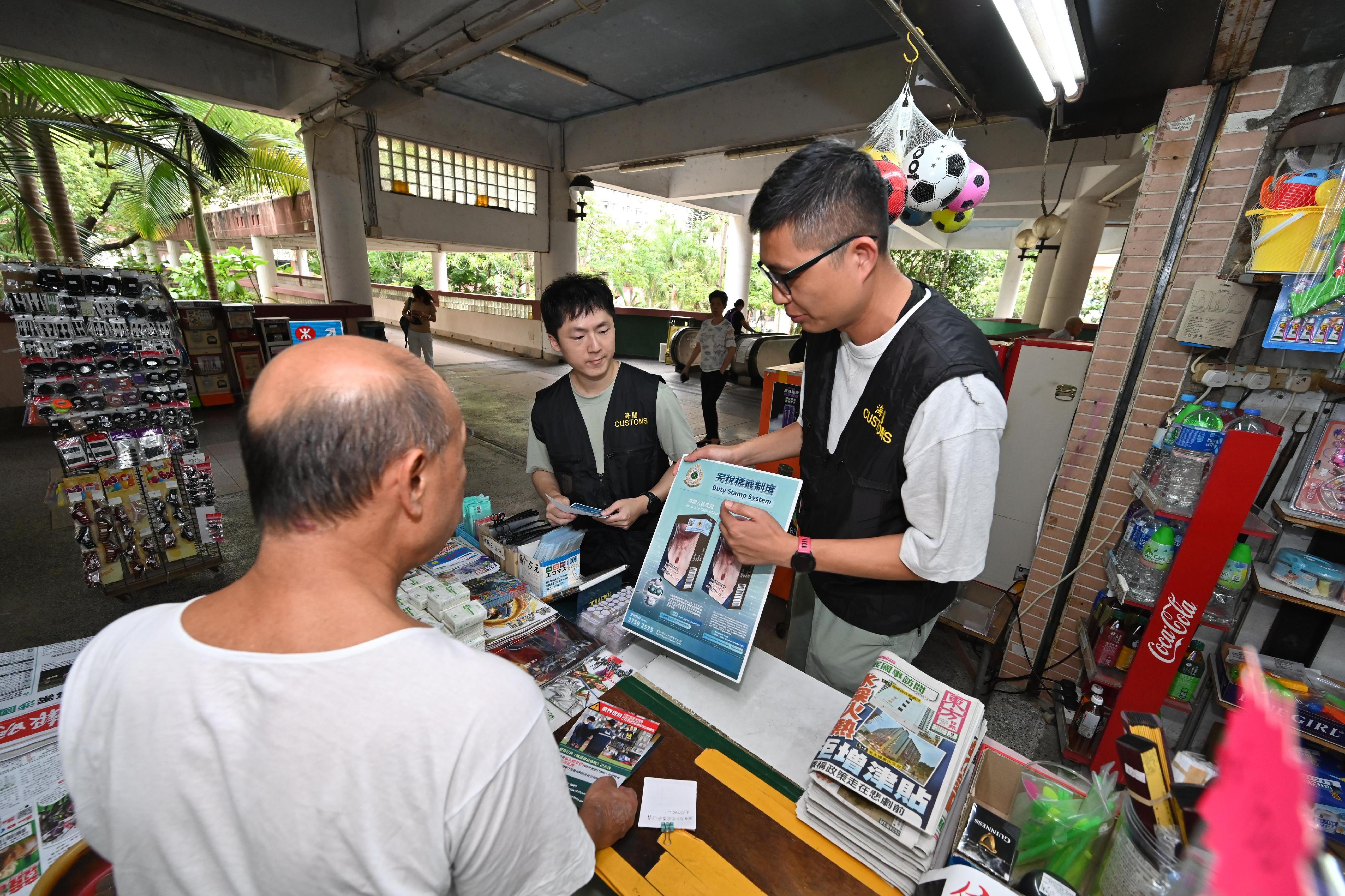 香港海關昨日(六月九日)與立法會議員張培剛、觀塘區議員、衞生署控煙酒辦公室、警務處及房屋署在觀塘翠屏(北)邨及秀茂坪邨進行聯合反私煙宣傳活動,並講解完稅標籤制度。圖示海關人員向香煙零售商販宣揚反私煙信息並介紹完稅標籤制度。