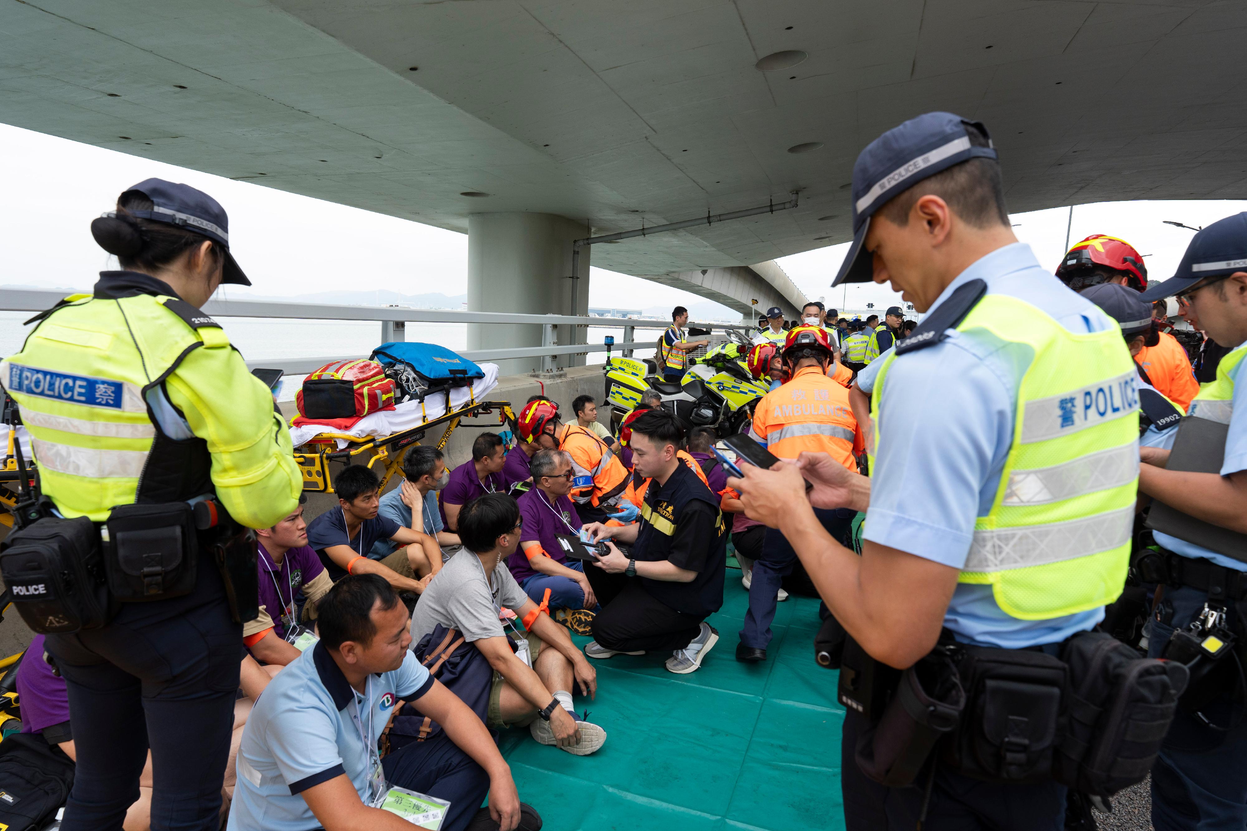警務處新界南總區今日 (六月十一日)聯同多個政府部門及機構在港珠澳大橋香港連接路進行代號「炬輝」(BRIGHTTORCH) 的跨部門重大事故演習。圖示入境事務處和警務處人員向傷者提供協助。