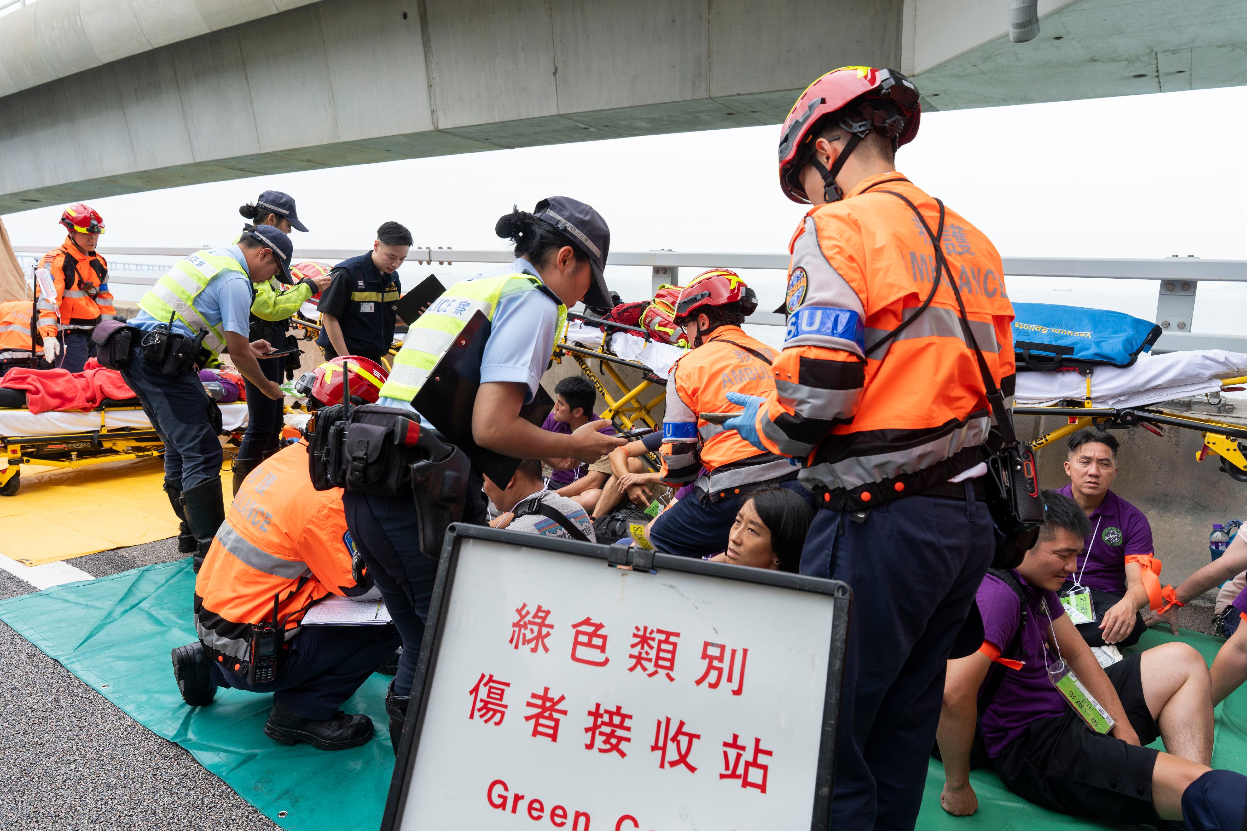 The New Territories South Region of the Hong Kong Police Force, together with various government departments and organisations, conducted an inter-departmental major incident exercise codenamed "BRIGHTTORCH" today (June 11) on the Hong Kong-Zhuhai-Macao Bridge Hong Kong Link Road. Photo shows ambulancemen treating injured persons and police officers gathering information at the triage.