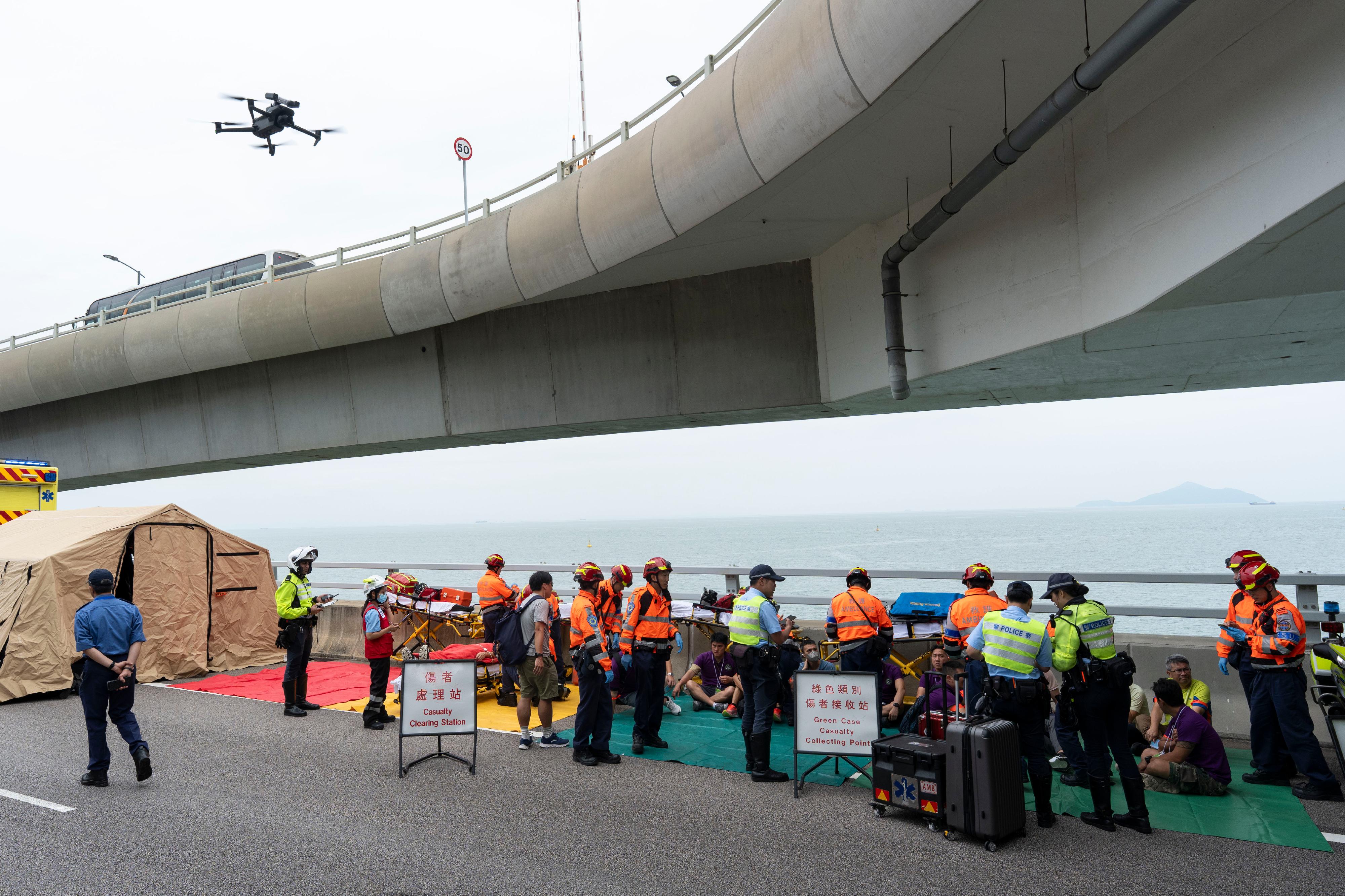 The New Territories South Region of the Hong Kong Police Force, together with various government departments and organisations, conducted an inter-departmental major incident exercise codenamed "BRIGHTTORCH" today (June 11) on the Hong Kong-Zhuhai-Macao Bridge Hong Kong Link Road. Photo shows officers establishing a command post and a casualty triage station at the scene.