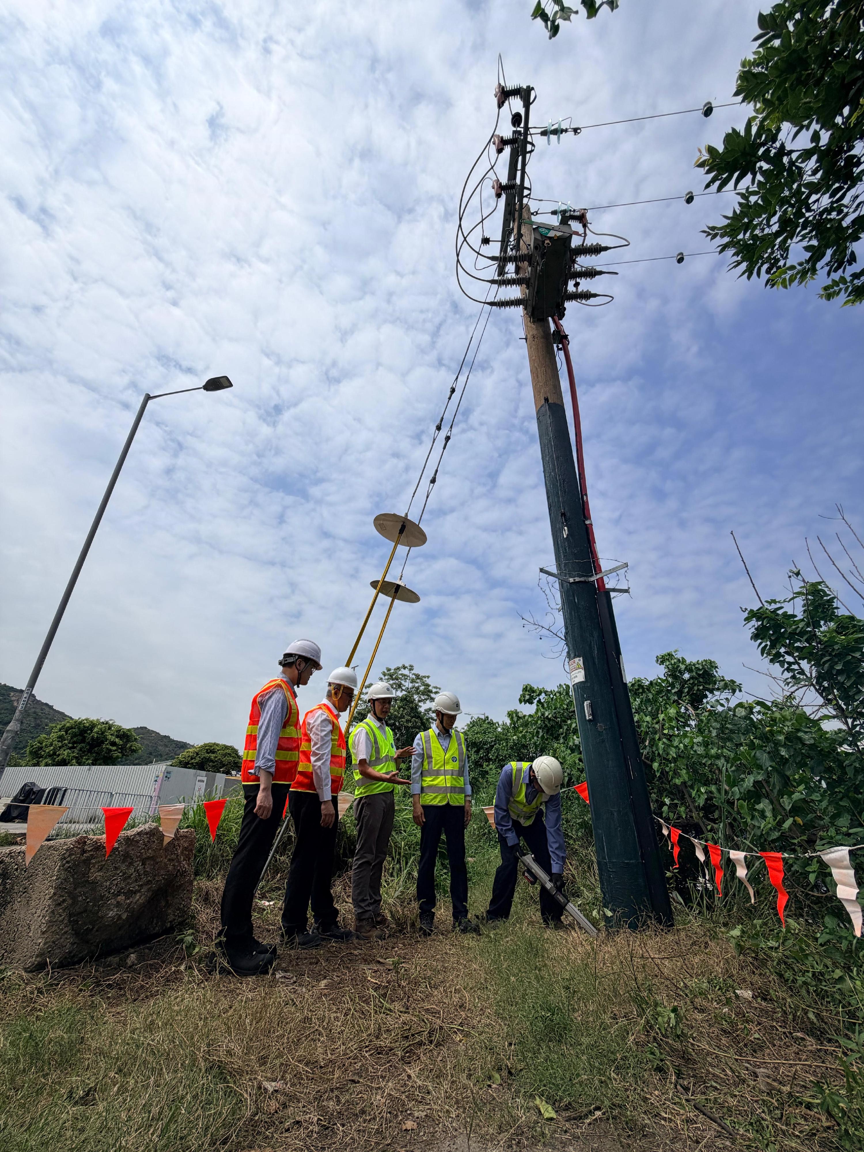 機電工程署署長潘國英(左二)今日(六月十二日)在中華電力有限公司(中電)高層人員陪同下,到大欖了解中電增強鄉郊地區戶外電線杆抵禦颱風能力的措施。