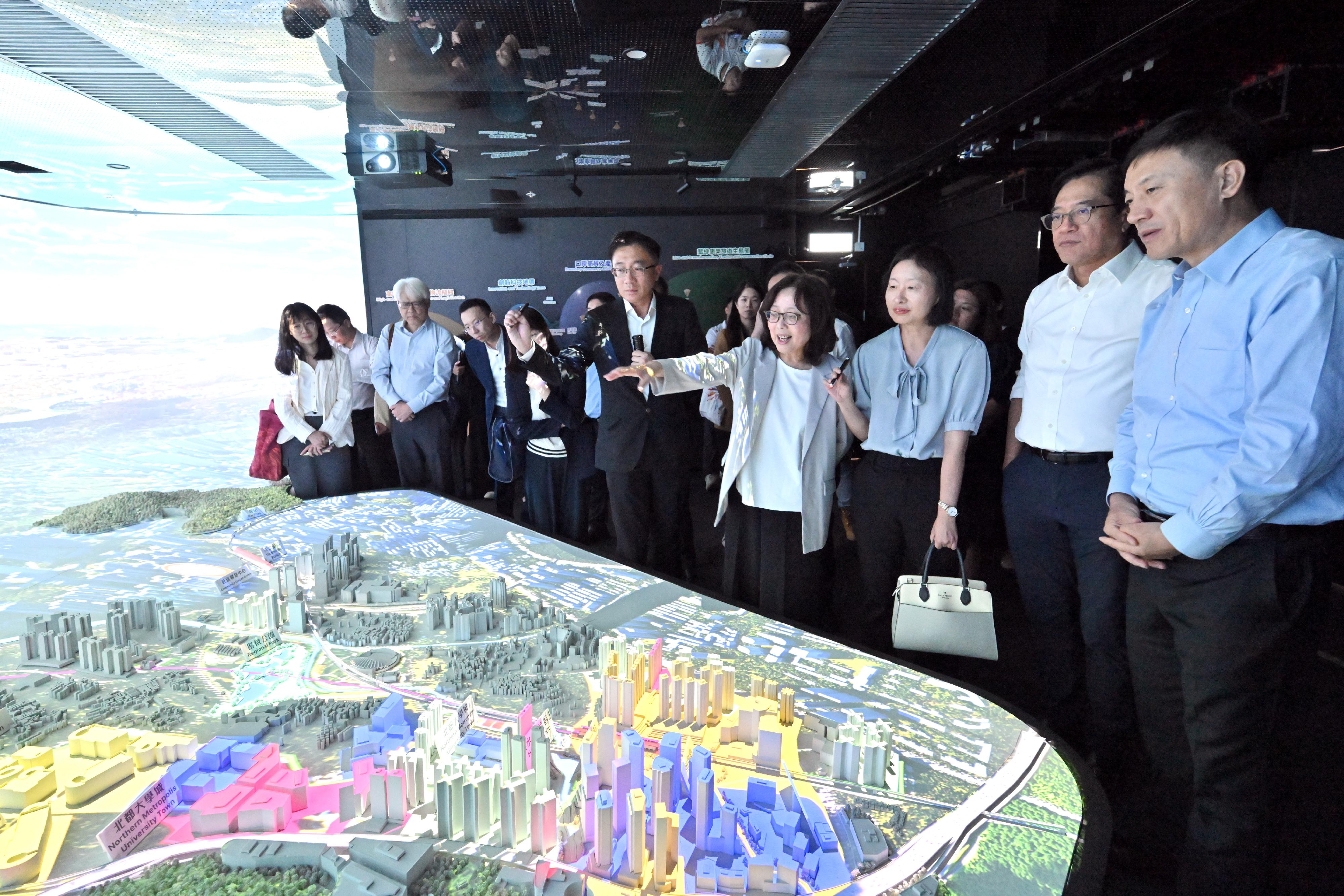 The Deputy Financial Secretary, Mr Michael Wong, and Vice Mayor of the Shenzhen Municipal People's Government Mr Tao Yongxin, leading delegations of the governments of the Hong Kong Special Administrative Region and Shenzhen respectively, held a meeting of the Task Force for Collaboration on the Northern Metropolis Development Strategy in Hong Kong today (June 12). Photo shows Mr Wong (second right), Mr Tao (first right), the Secretary for Development, Ms Bernadette Linn (fourth right), the Director of the Northern Metropolis Co-ordination Office, Ms Linda So (third right) and the HKSAR and Shenzhen delegations visiting the exhibition gallery of the Hung Shui Kiu/Ha Tsuen New Development Area Community Liaison Centre after the meeting, where they toured the immersive digital experience zone and viewed a sand table model to learn about the overall planning of the new development area.