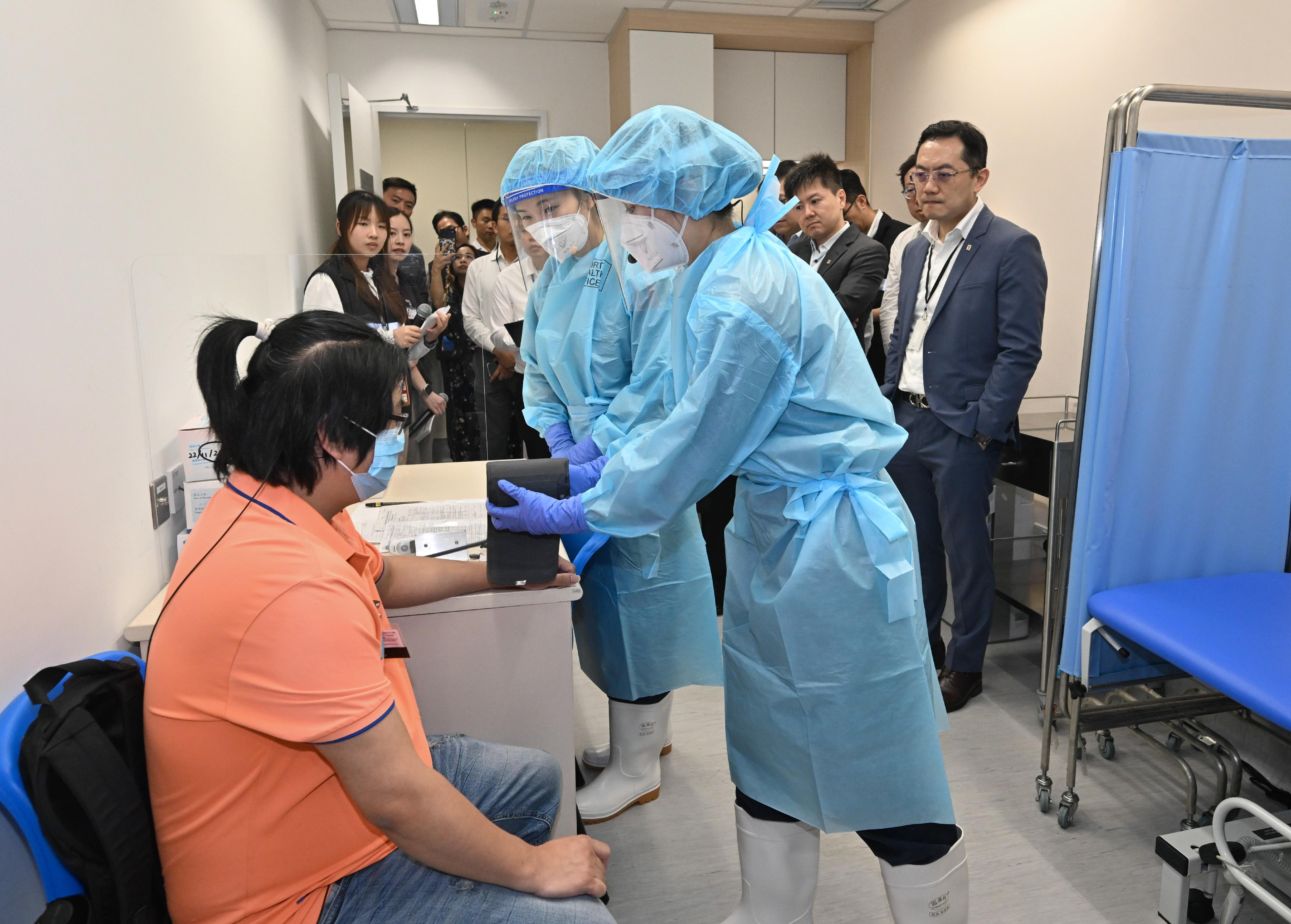 The Centre for Health Protection (CHP) of the Department of Health (DH) today (June 16) conducted a public health exercise codenamed "Charoite" in collaboration with various relevant government departments and organisations to strengthen stakeholders' response and co-ordination capabilities in handling suspected imported cases of Ebola disease and to enhance awareness among all units about the prevention and management of public health emergencies. Photo shows a Port Health Division officer under the CHP conducting health assessment for a passenger exhibiting symptoms at a health post of Hong Kong International Airport in a simulated scenario. Looking on are the Director of Health, Dr Ronald Lam (first right), the Controller of the CHP of the DH, Dr Edwin Tsui (second right), and other observers.