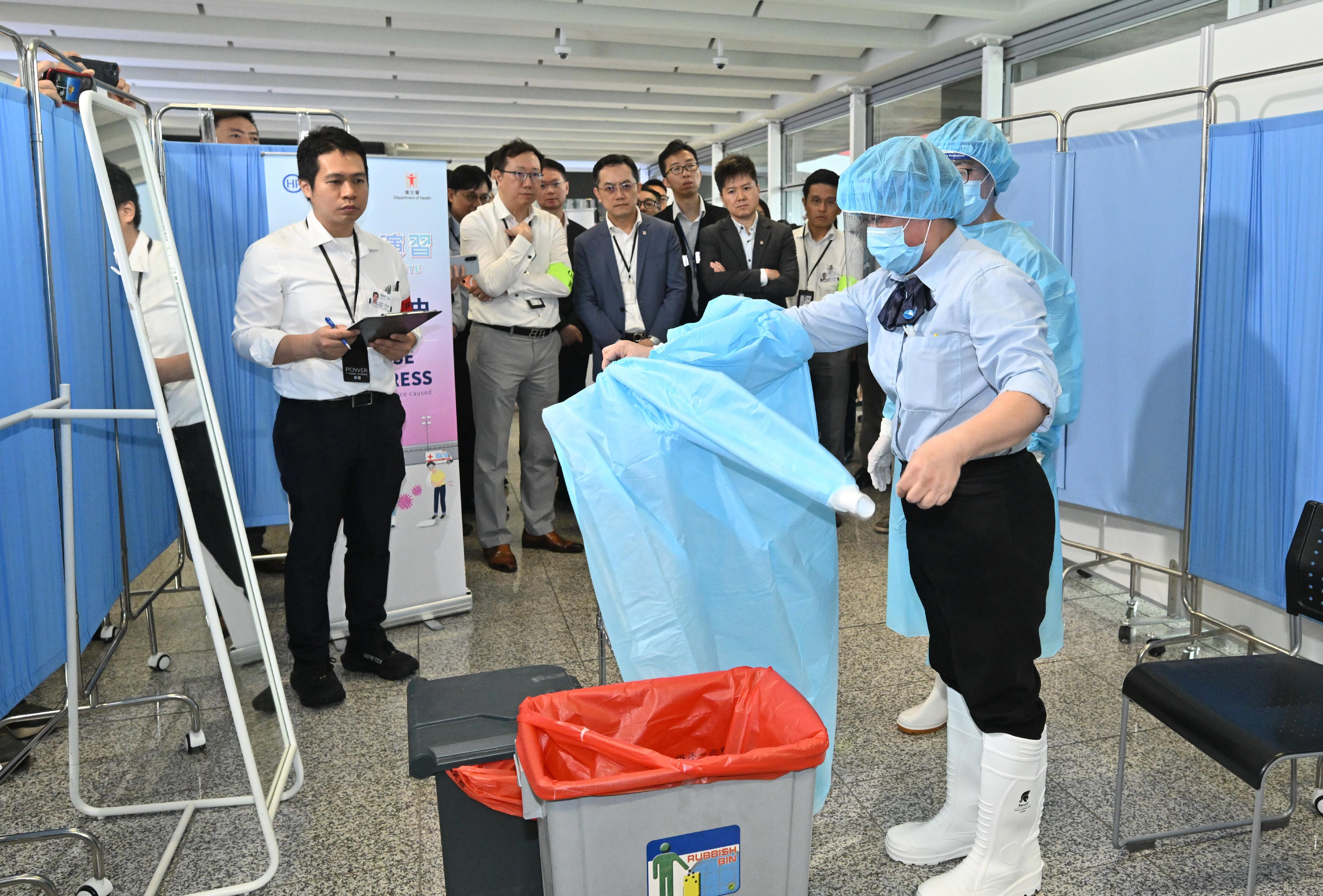 The Centre for Health Protection (CHP) of the Department of Health (DH) today (June 16) conducted a public health exercise codenamed "Charoite" in collaboration with various relevant government departments and organisations to strengthen stakeholders' response and co-ordination capabilities in handling suspected imported cases of Ebola disease and to enhance awareness among all units about the prevention and management of public health emergencies. Photo shows the Director of Health, Dr Ronald Lam (third left); the Controller of the CHP of the DH, Dr Edwin Tsui (fourth left); and the Head of the Infection Control Branch of the CHP, Dr Edmond Ma (second left), inspecting the doffing procedures of frontline staff and related infection control measures during the exercise.