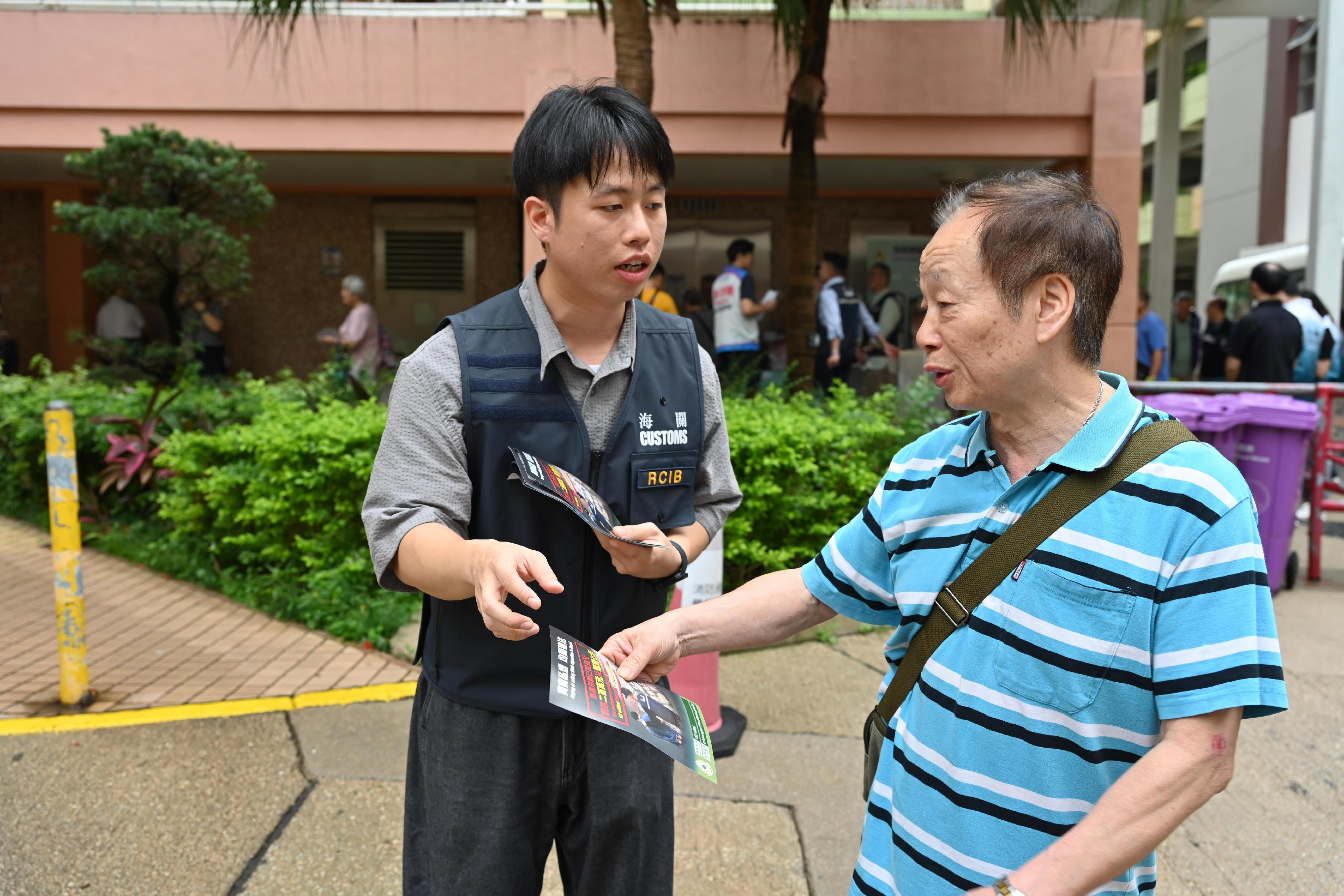 Hong Kong Customs today (June 17) conducted a joint anti-illicit cigarette publicity campaign with members of the Sha Tin District Council, the Tobacco and Alcohol Control Office of the Department of Health, the Hong Kong Police Force and the Housing Department in Mei Tin Estate in Tai Wai. Customs also publicised the Duty Stamp System. Photo shows a Customs officer explaining anti-illicit cigarette messages to a resident.