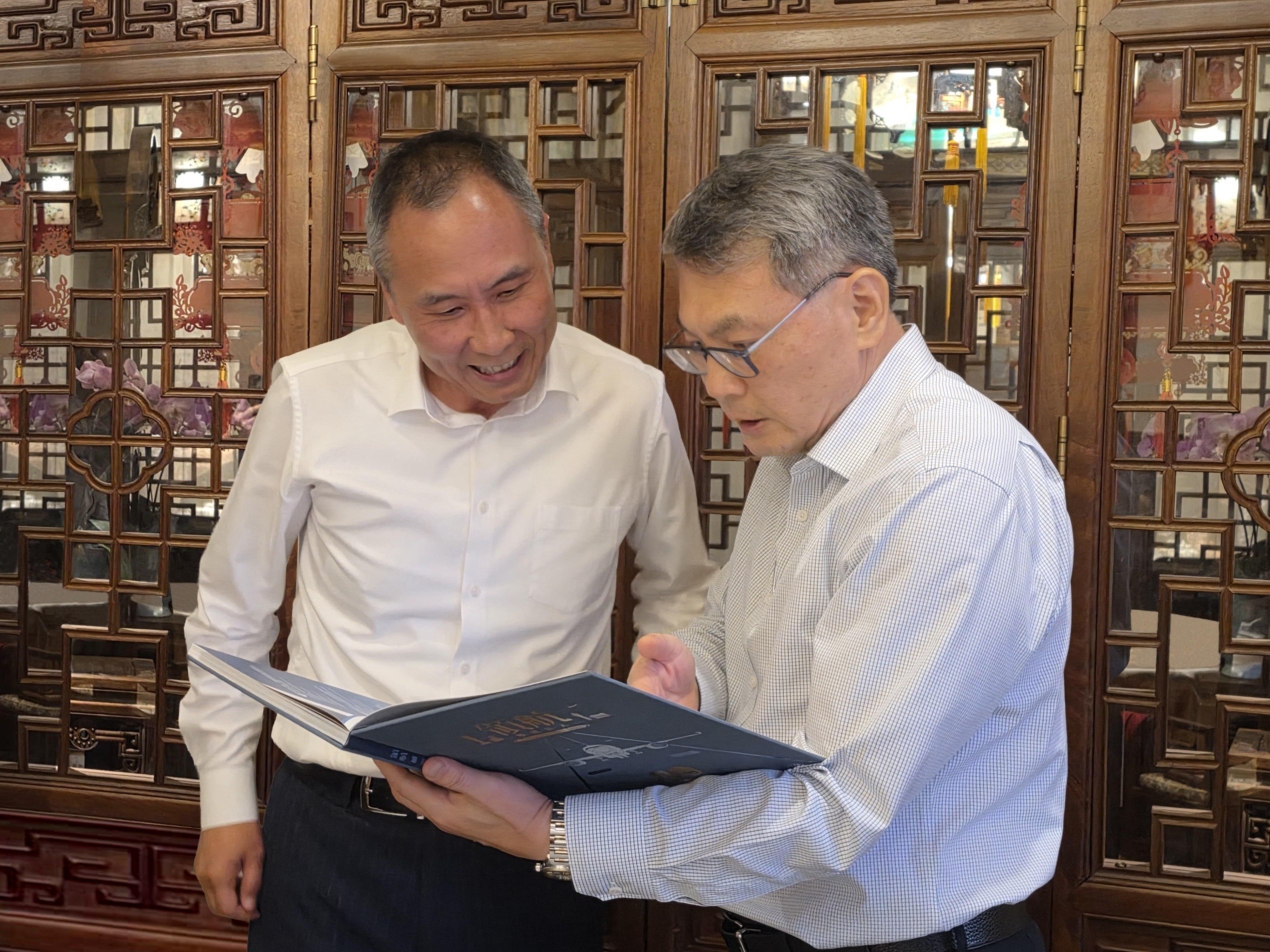 The Director-General of Civil Aviation, Mr Victor Liu, arrived in Beijing yesterday (June 17) and began his visit programme. Mr Liu met with the Director-General of the Air Traffic Management Bureau of the Civil Aviation Administration of China, Mr Miao Xuan, to discuss on fostering co-operation in air traffic management. Photo shows Mr Liu (right) sharing with Mr Miao (left) the precious photos featured in the Civil Aviation Department 80th anniversary commemorative book, "Pioneering New Skies", and the civil aviation development of Hong Kong.

