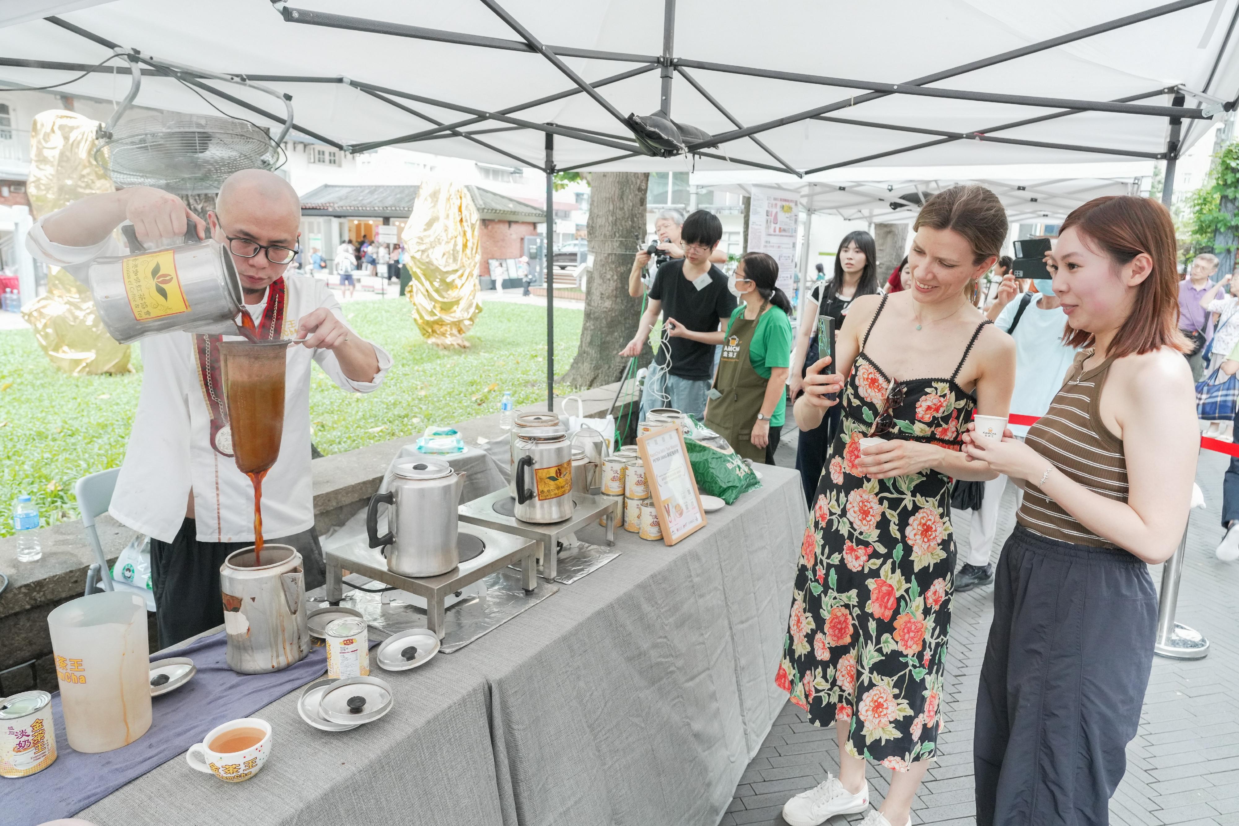 The Intangible Cultural Heritage Office of the Leisure and Cultural Services Department is holding the "ICH Cuisine" Carnival at the Oil Street Art Space today (June 20) and tomorrow (June 21). Photo shows the demonstration of Hong Kong-style milk tea making technique, in which a master repeatedly pours water into the cloth colander, which contains tea leaves, and then pours the hot tea into a cup of evaporated milk.