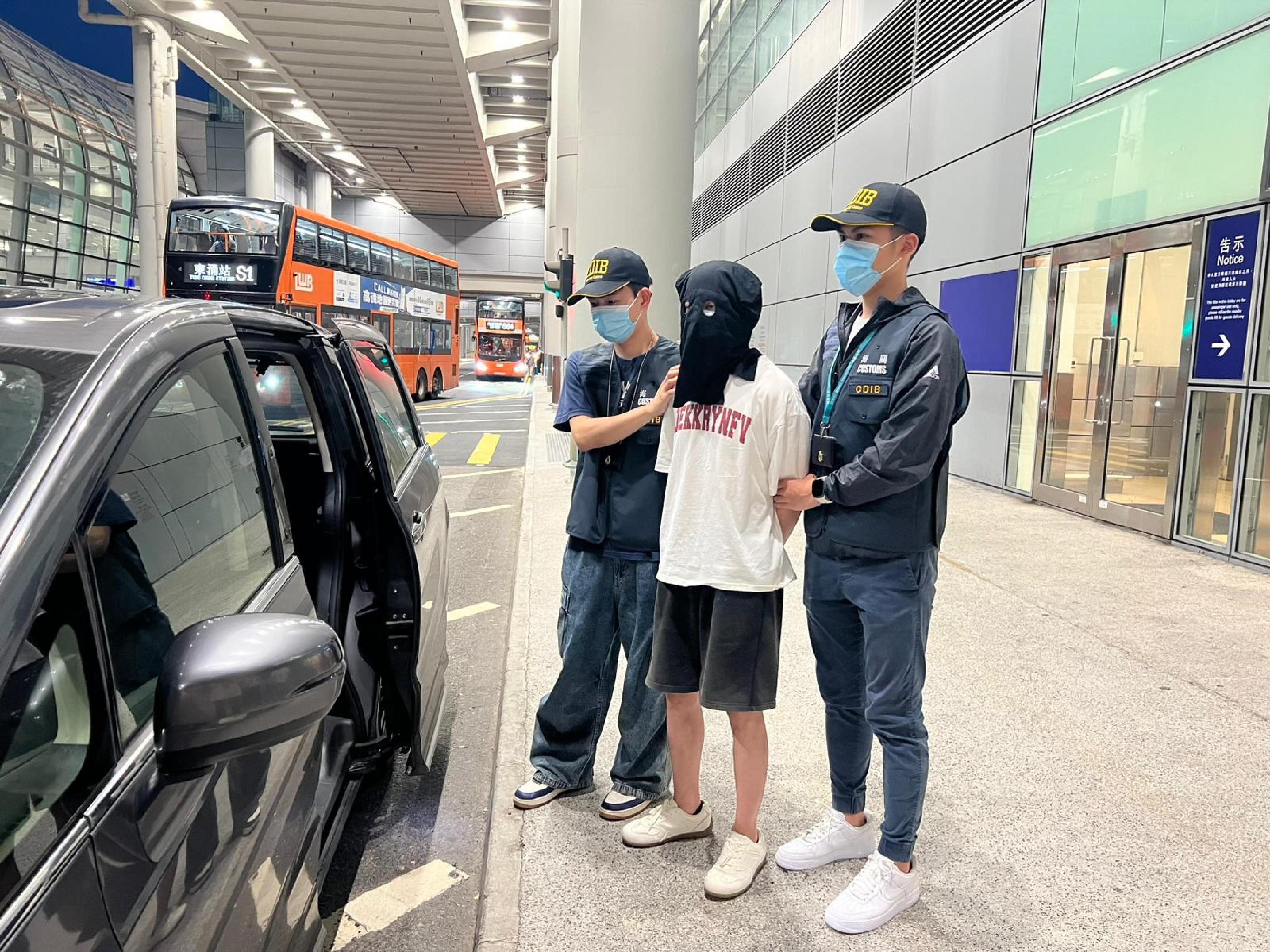 香港海關今日(六月二十二日)在香港國際機場偵破一宗涉及行李藏毒的販毒案件,檢獲約十二公斤懷疑大麻花,市值約二百一十萬元。圖示案件中的被捕人士(中)。