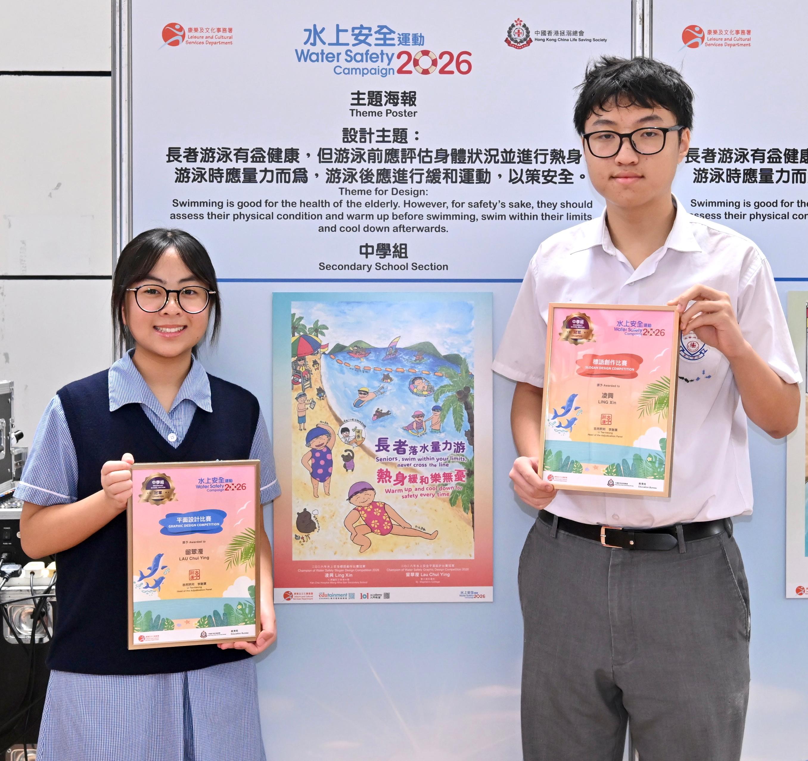 A prize presentation ceremony for the Water Safety Campaign 2026 slogan and graphic design competitions, jointly organised by the Leisure and Cultural Services Department and the Hong Kong China Life Saving Society, was held today (June 27). Photo shows the champion of the secondary school section in the graphic design competition, Lau Chui-ying (left) with her winning entry, and the champion of the secondary school section in the Chinese slogan competition, Ling Xin (right).
