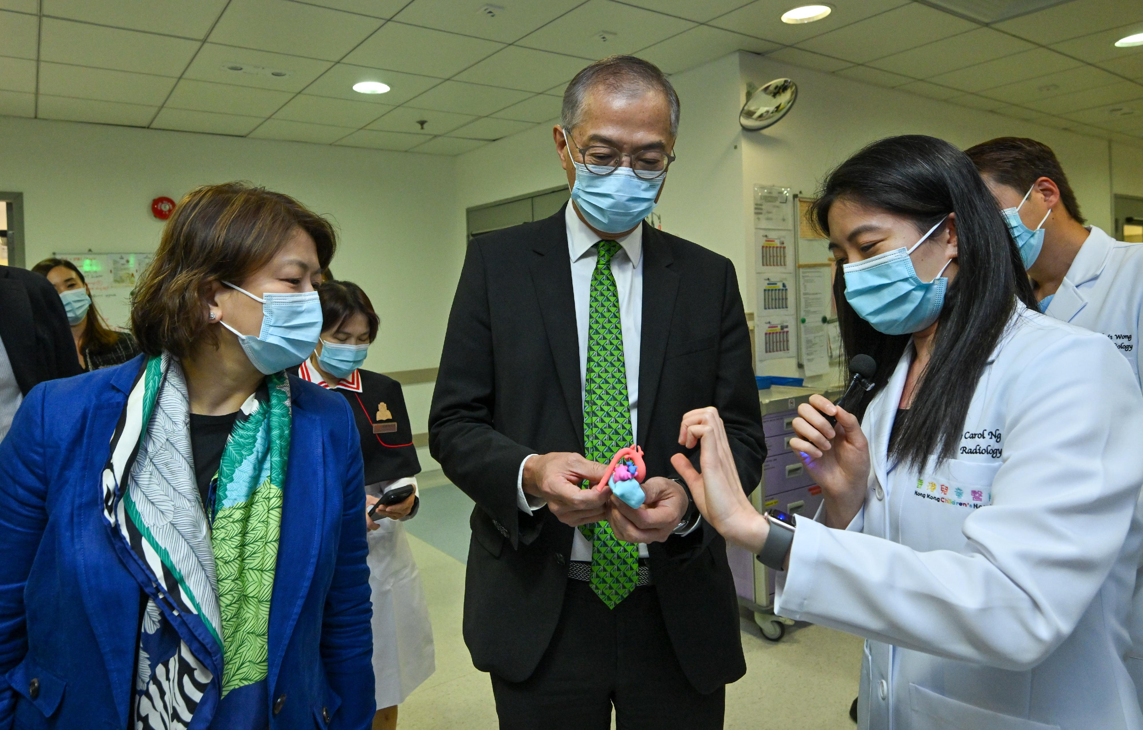 The Secretary for Health, Professor Lo Chung-mau (centre), visits the Hong Kong Children's Hospital today (July 3), and is briefed by a healthcare personnel on a 3D model illustrating congenital heart disease. Looking on is the Chief Executive of the Hospital Authority, Dr Libby Lee (left).