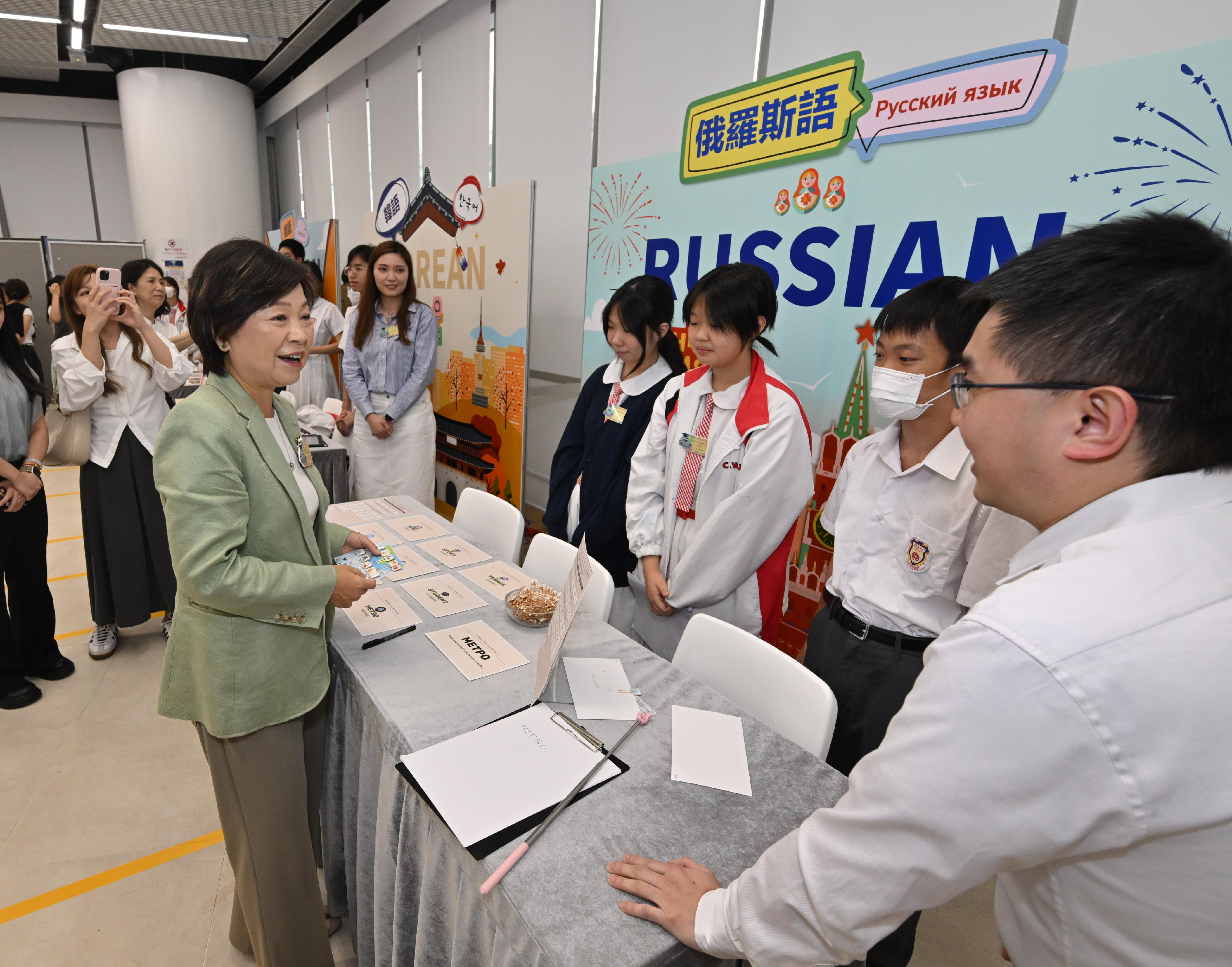 教育局今日(七月十一日)舉辦「學展同樂:其他語言體驗日」。圖示教育局局長蔡若蓮博士(左)在攤位與學生互動。