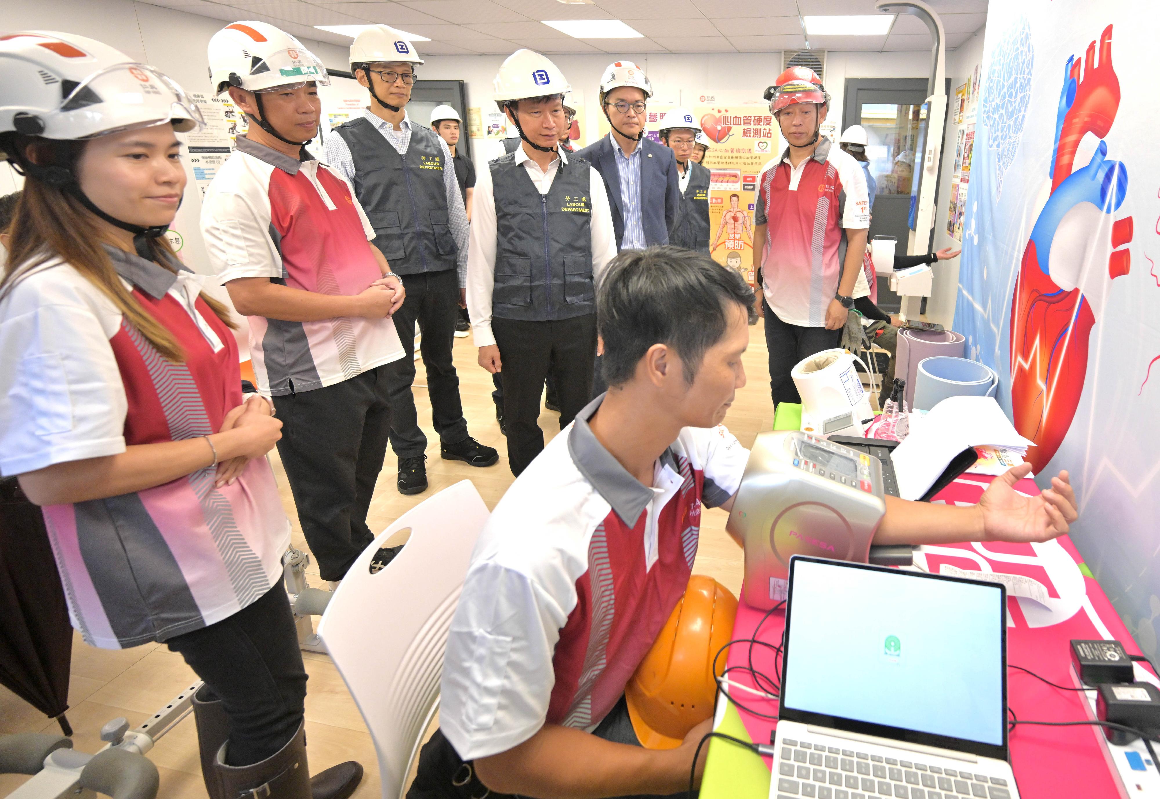 The Commissioner for Labour, Mr Sam Hui, and the Deputy Commissioner for Labour (Occupational Safety and Health), Mr Ivanhoe Chang, visited a construction site in To Kwa Wan today (July 17) to learn about anti-smoking measures implemented by a contractor. Photo shows Mr Hui (fourth left) and Mr Chang (third left) inspecting a health check station on the construction site to learn about the health protection measures implemented by the contractor for workers, including encouraging them to quit smoking.
